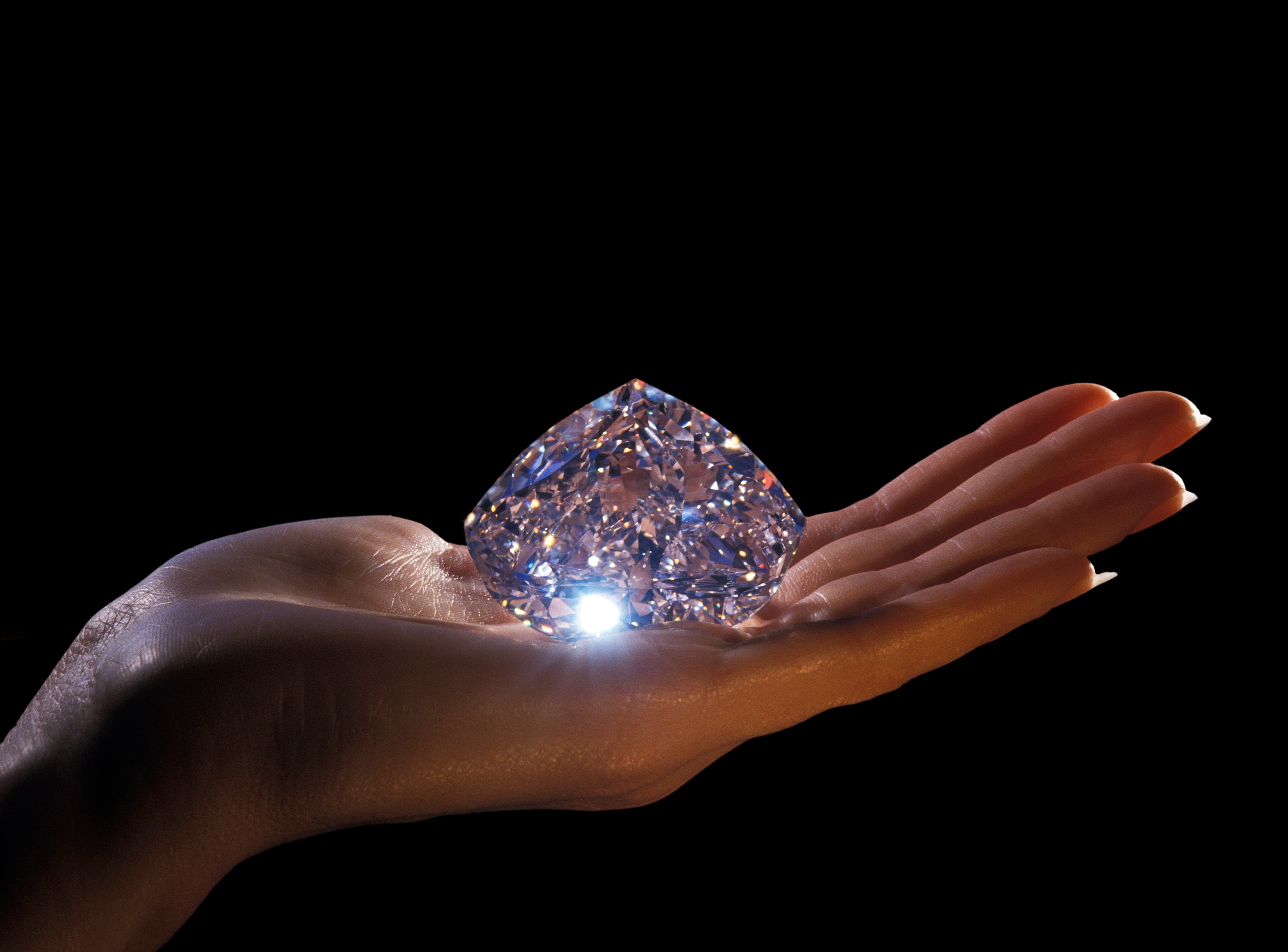 a gigantic diamond rest on the palm of a hand