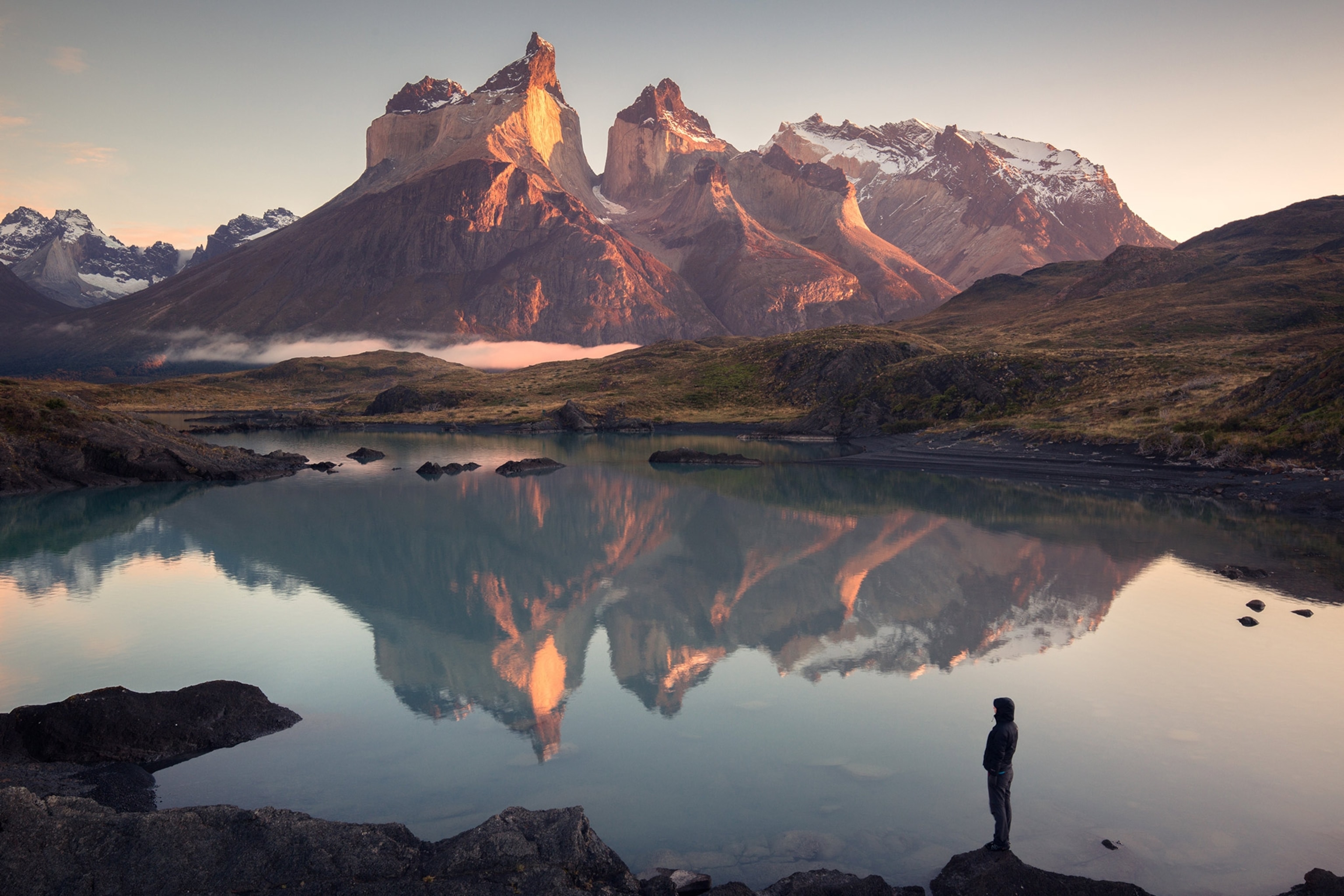 a hiker looking at sunrise over Torres del Paine, Chile