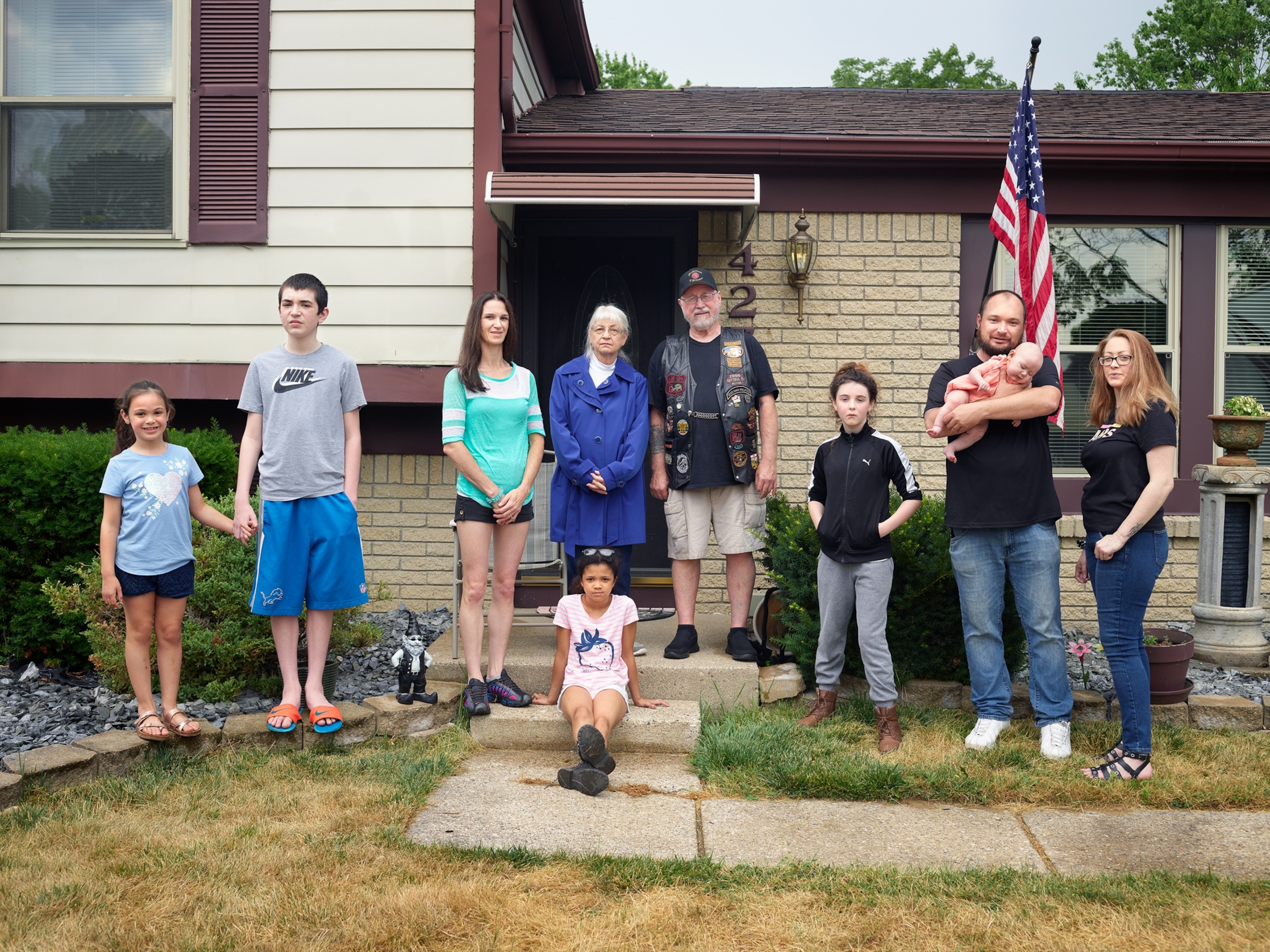 big family with children posing by the house front door.