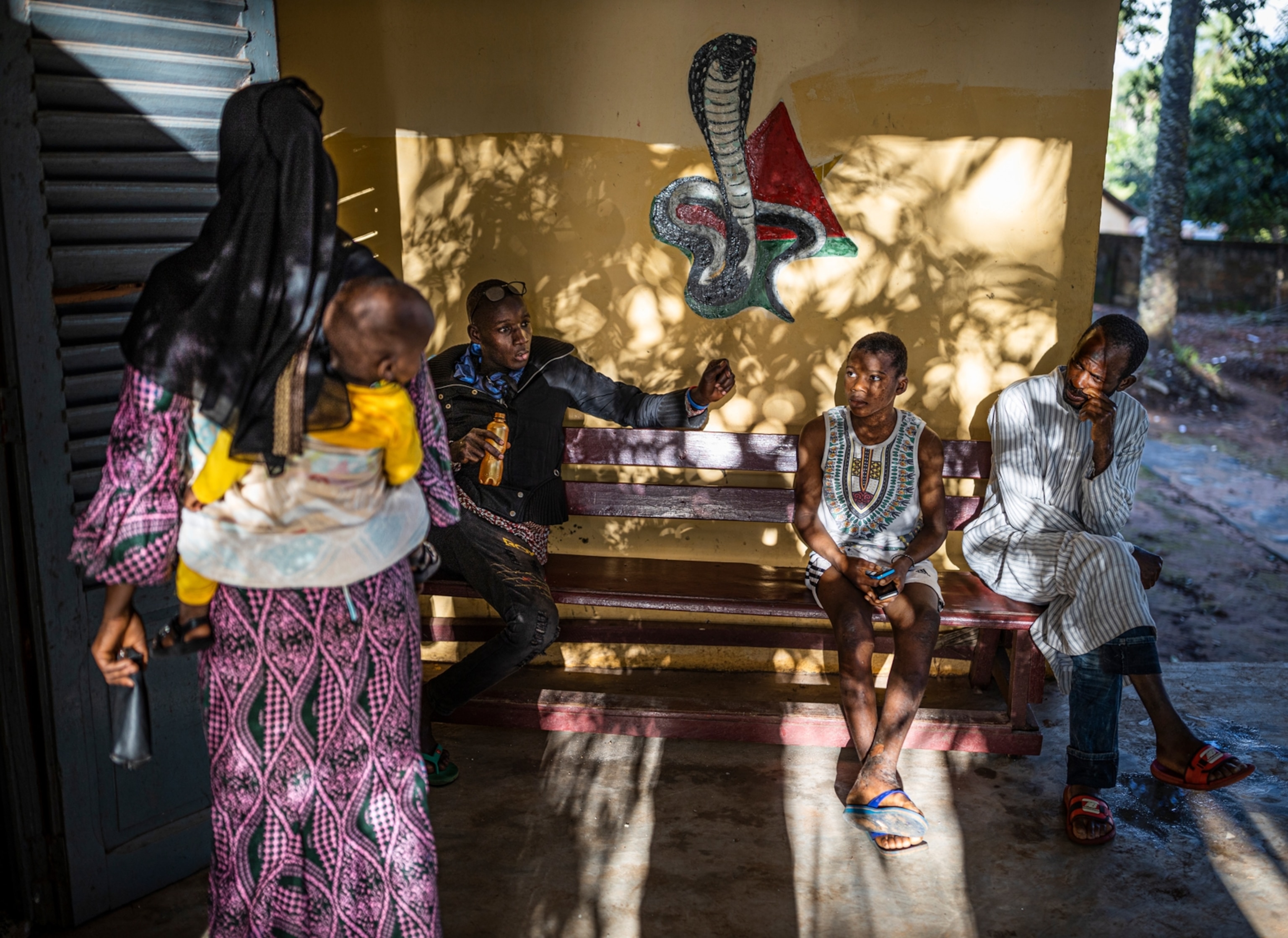 A group of villagers wait outside a rural snakebite clinic in Guinea