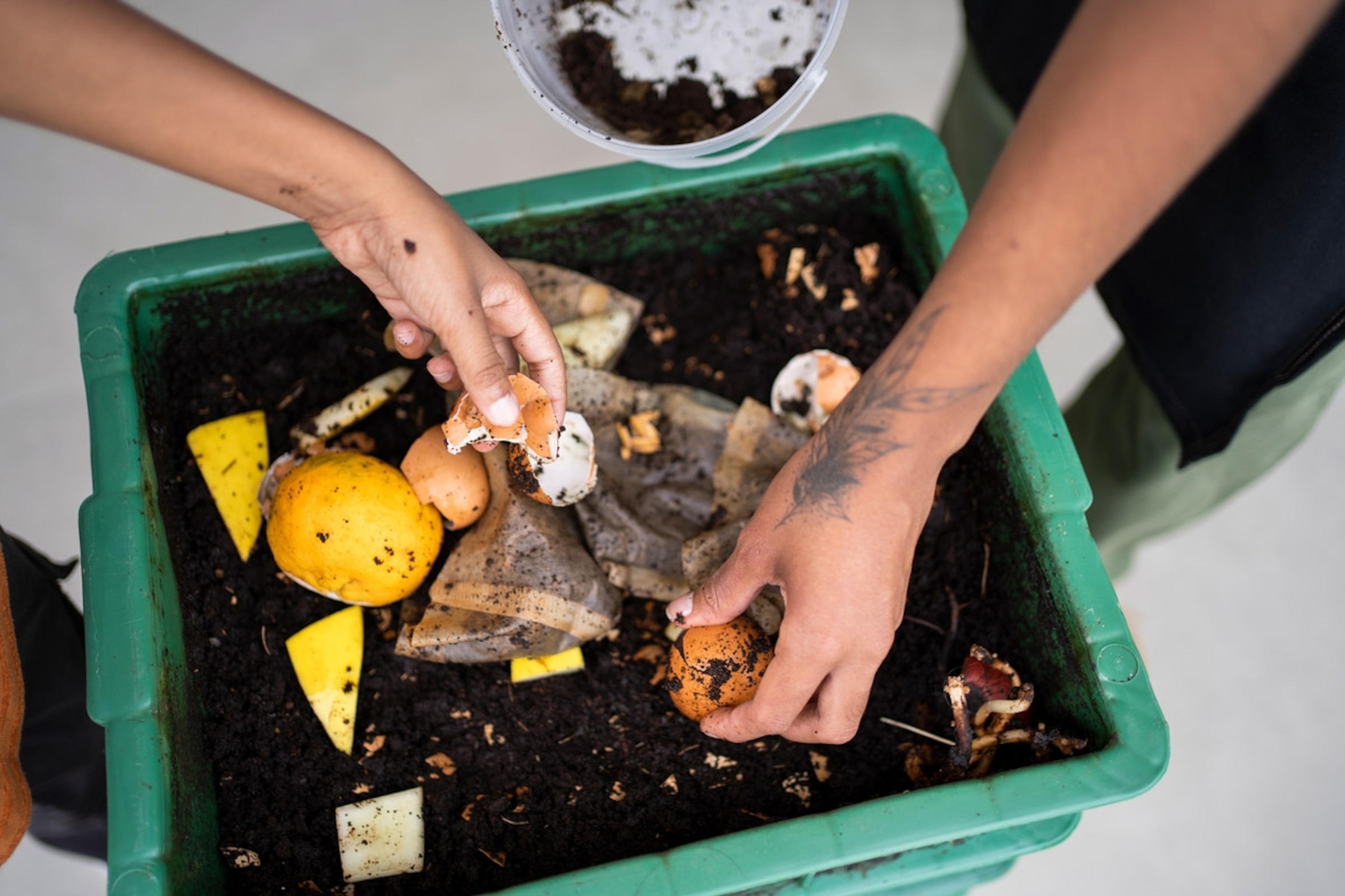 African american young woman and her younger brother making compost from leftovers. Sustainability concept. Brazil
