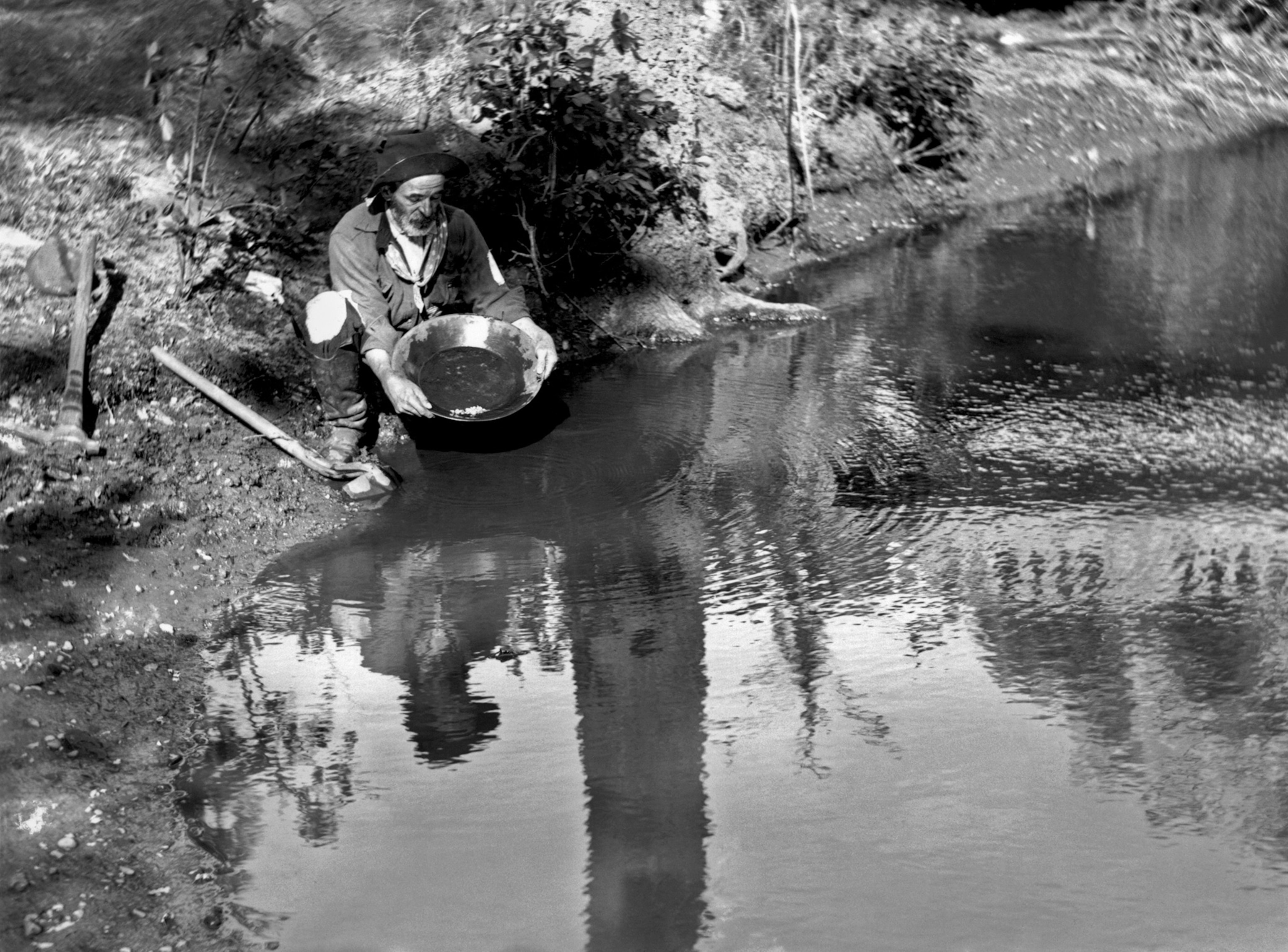 A black and white image kneeling while searching for gold.
