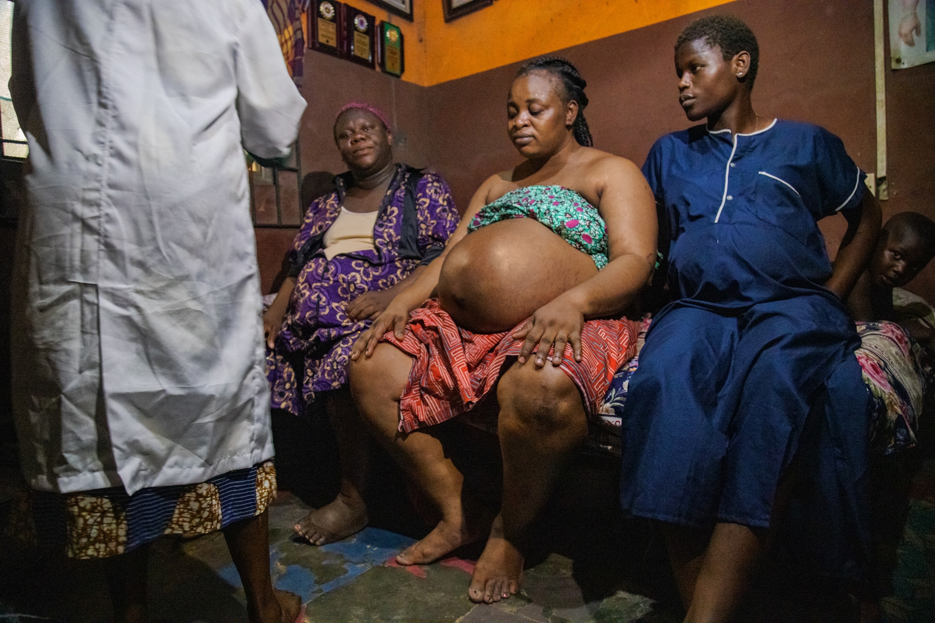 Picture of pregnant, women showing her belly to the midwife, and her family.