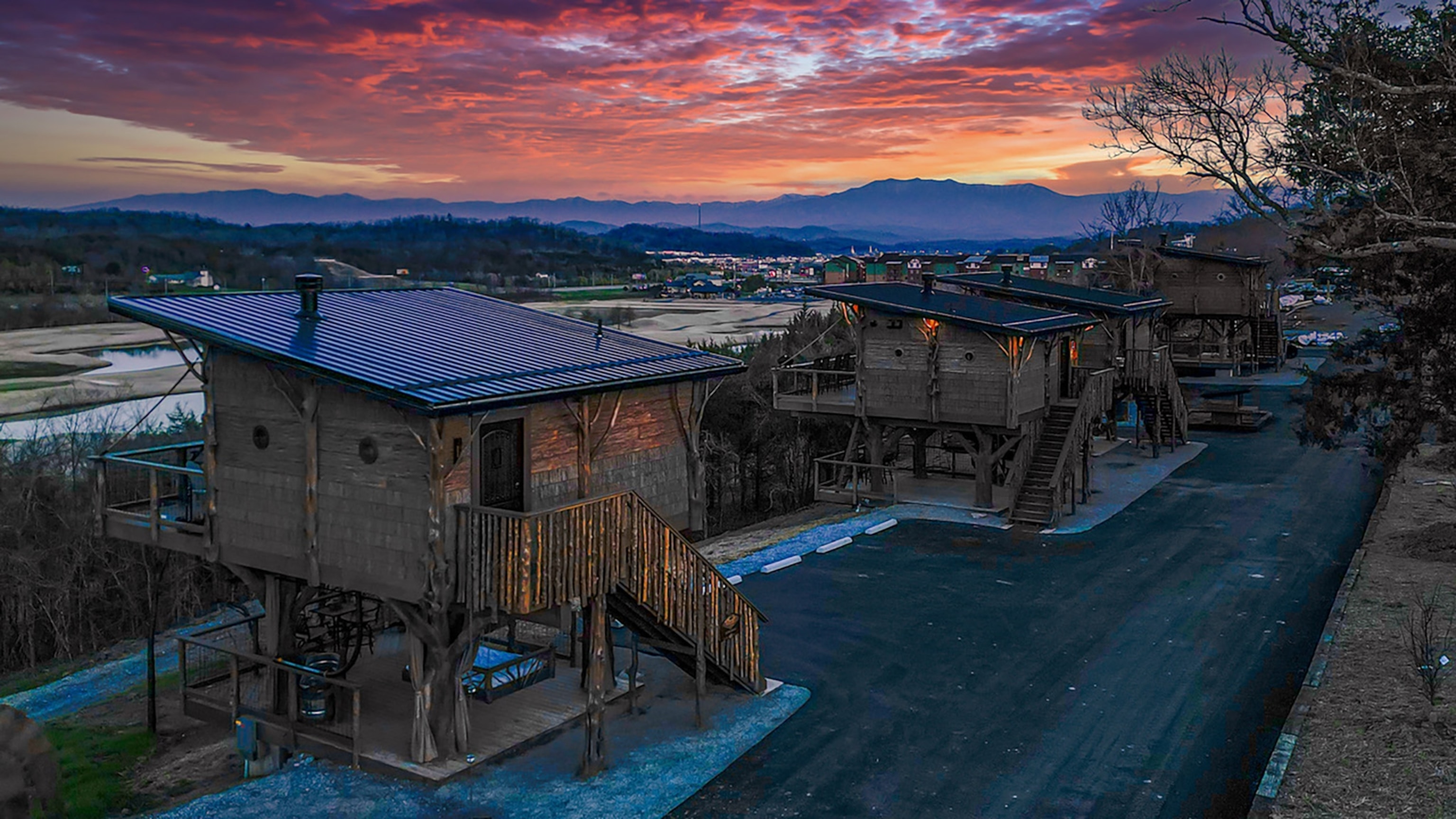 A row of wooden lodges under a colorful sunset.