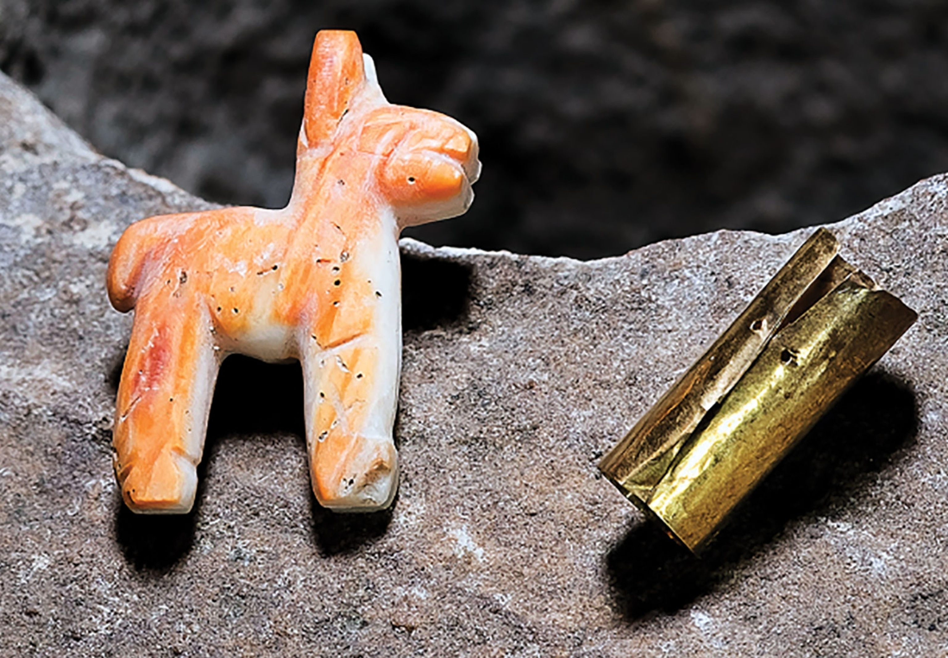 a small llama figuring and gold cylinder