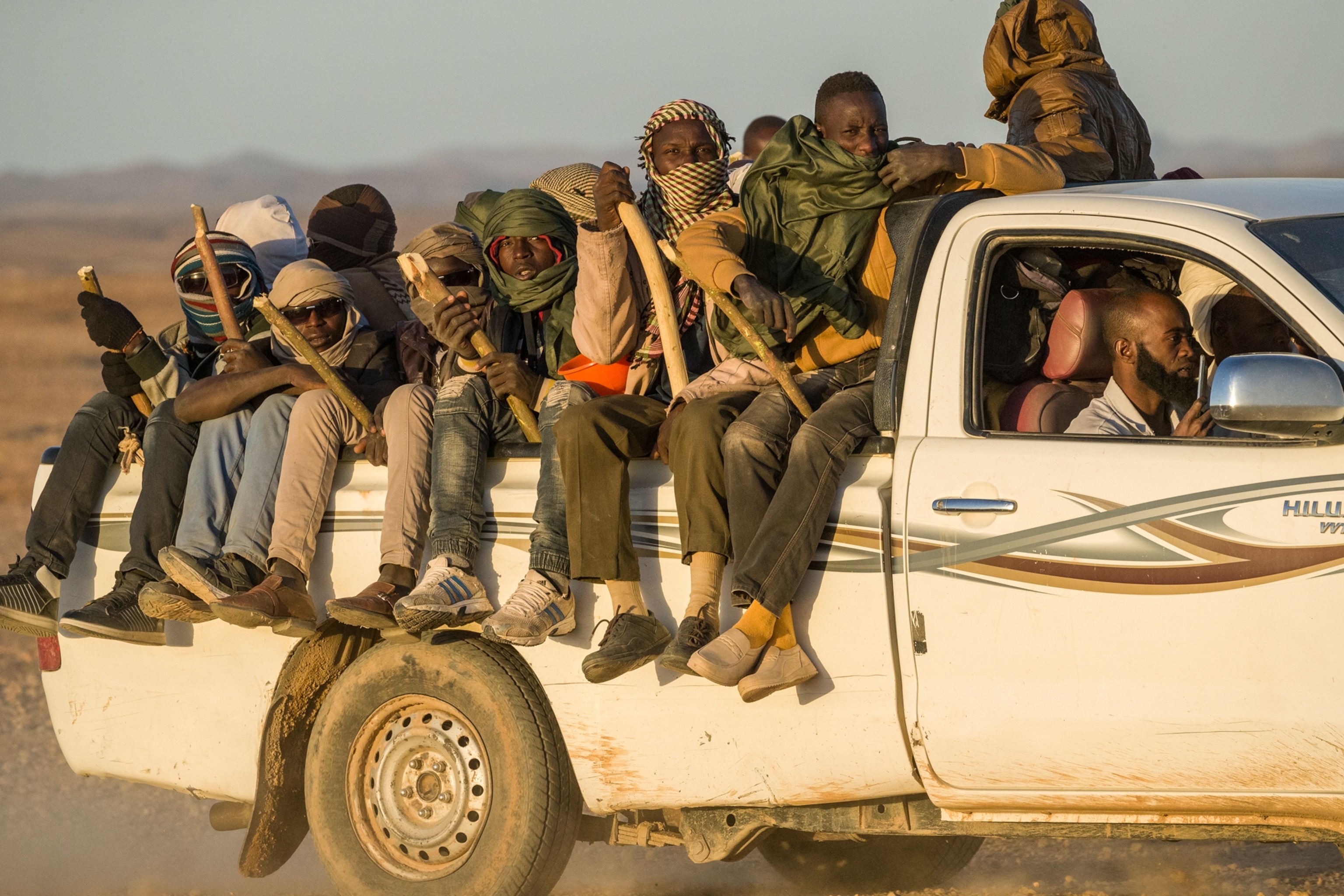 men holding sticks on a white pick up
