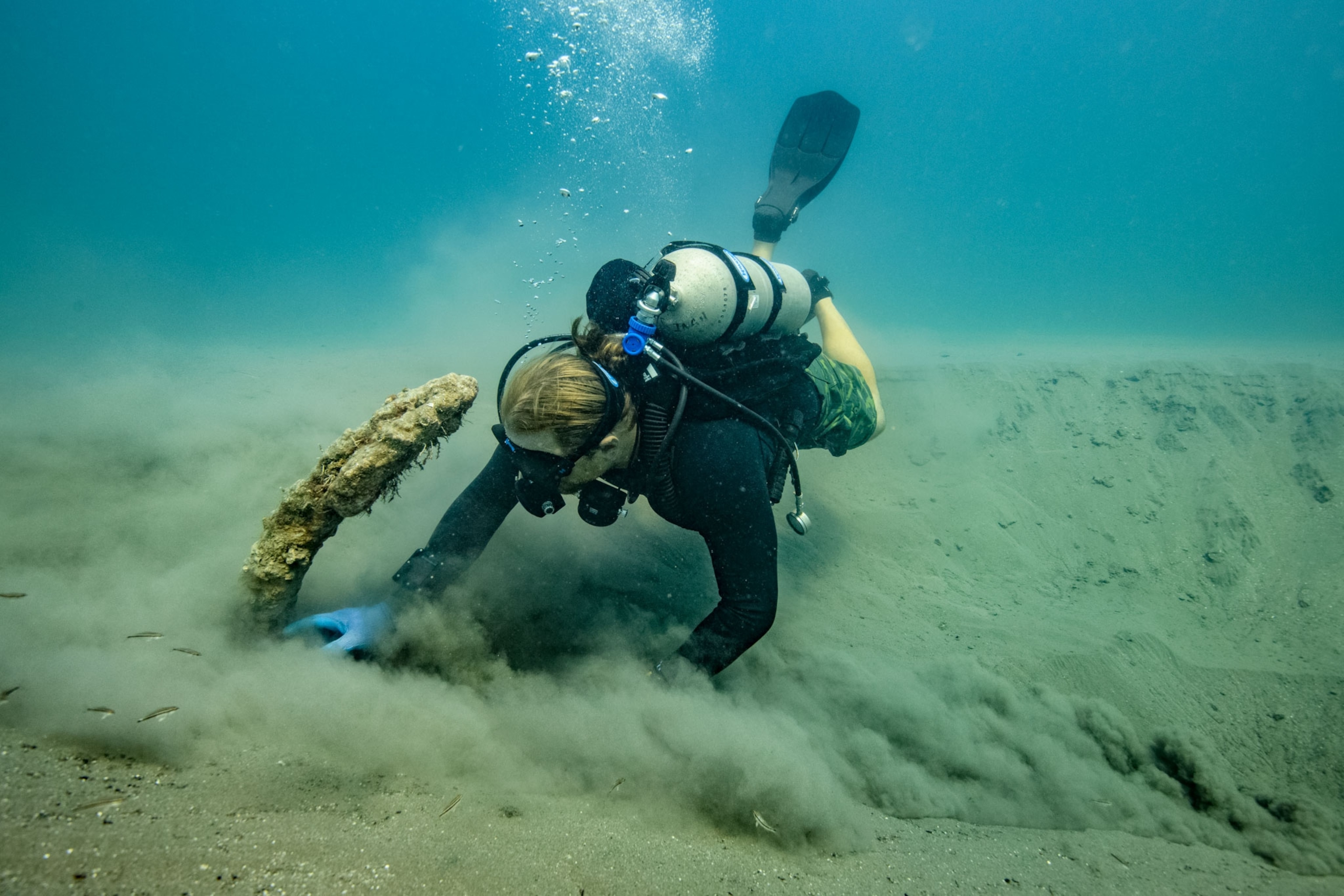 archaeologist fanning sand from anchor