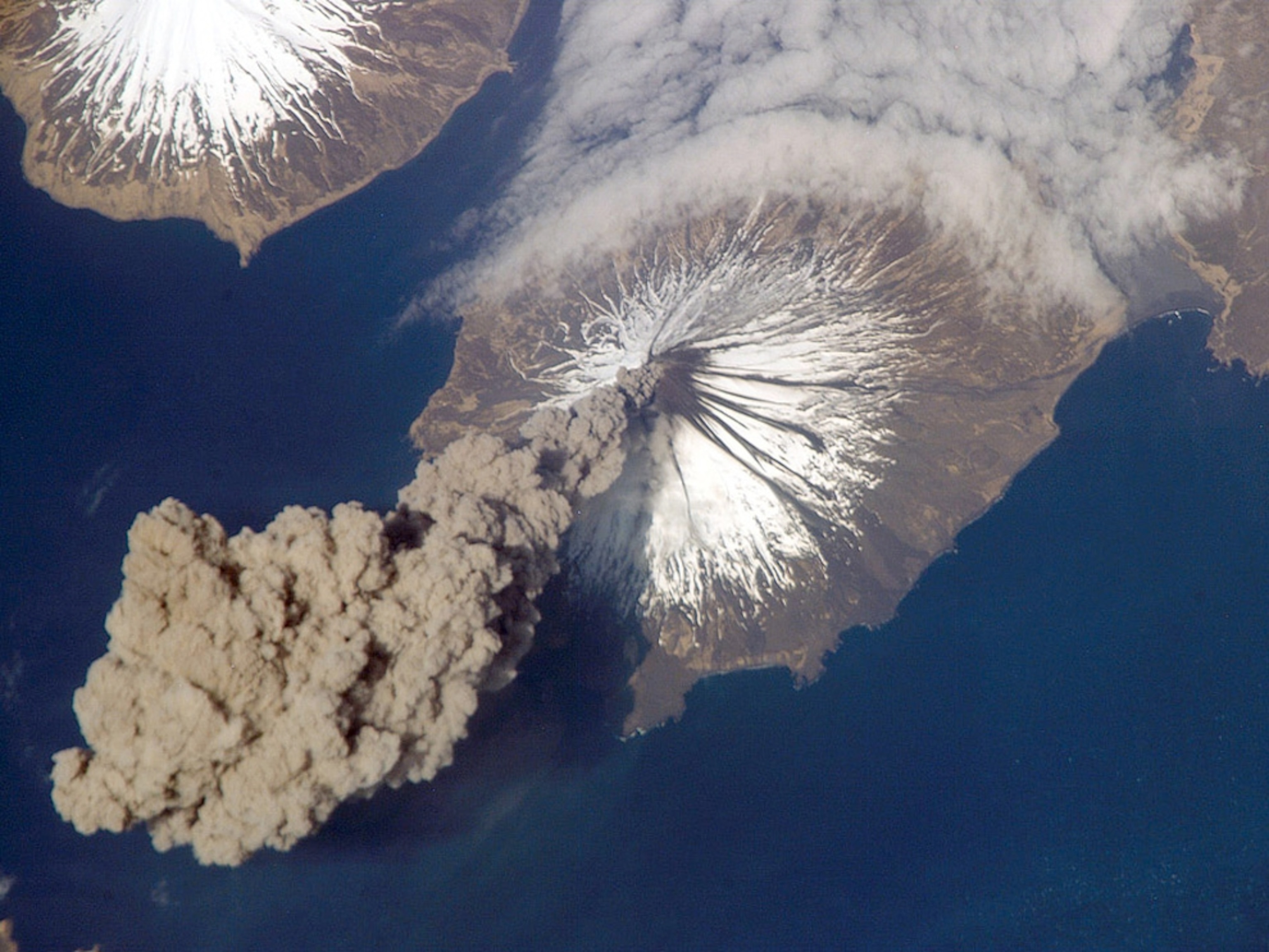 A plume of ash rises over the ocean