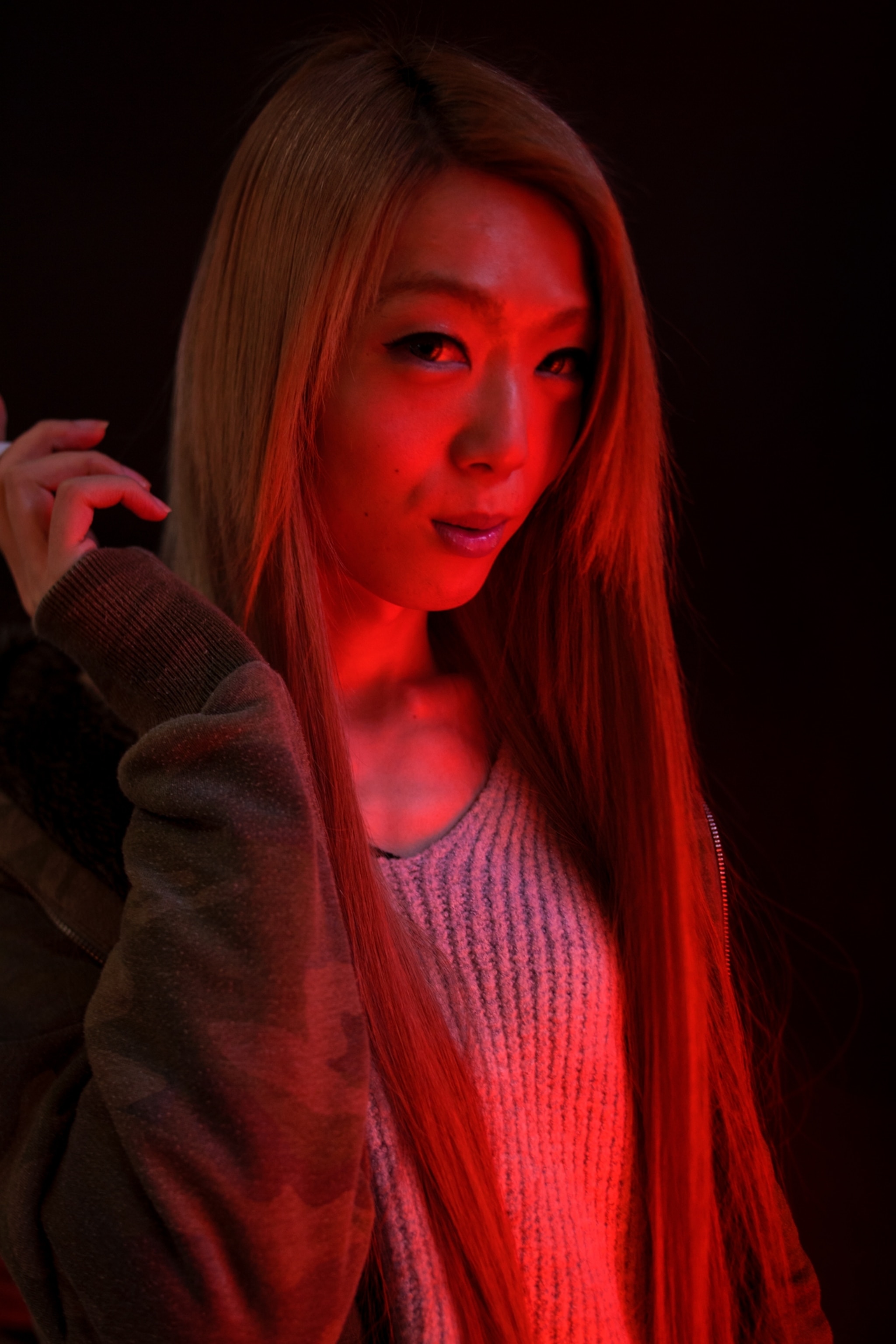 a woman standing against a black background cast in red neon light