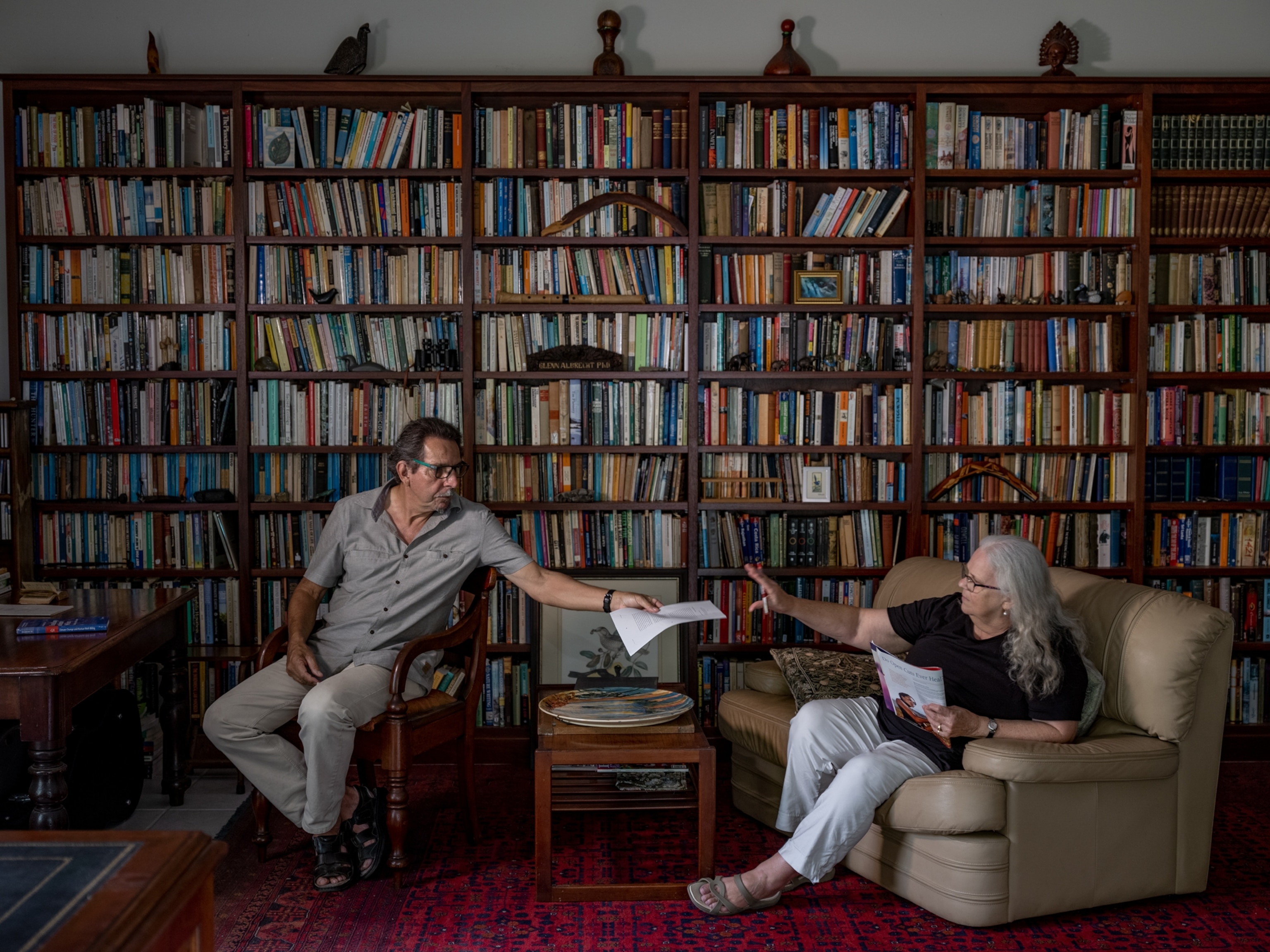 man and woman sitting against a wall of books