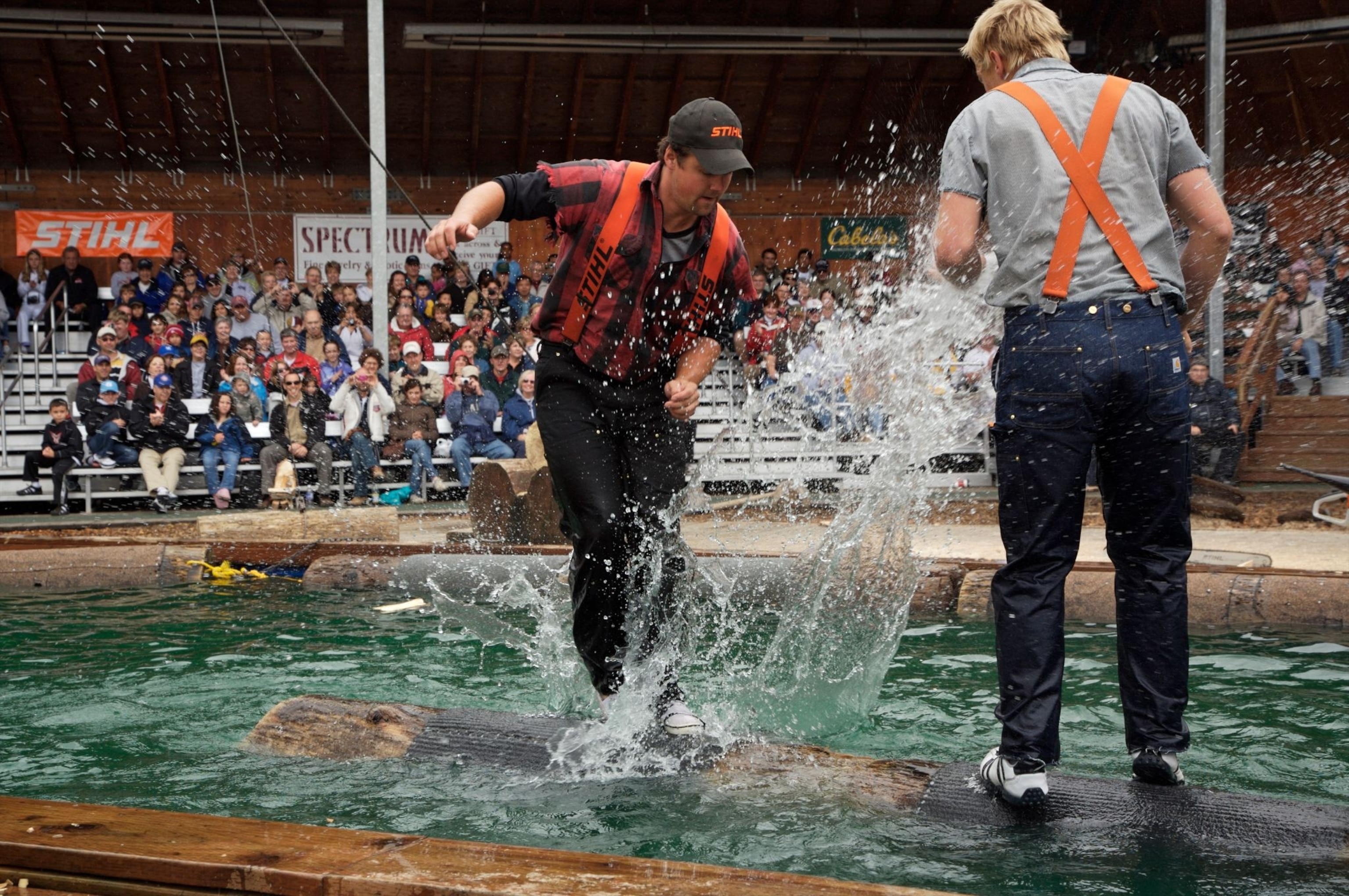 Two men try to stand on a floating log