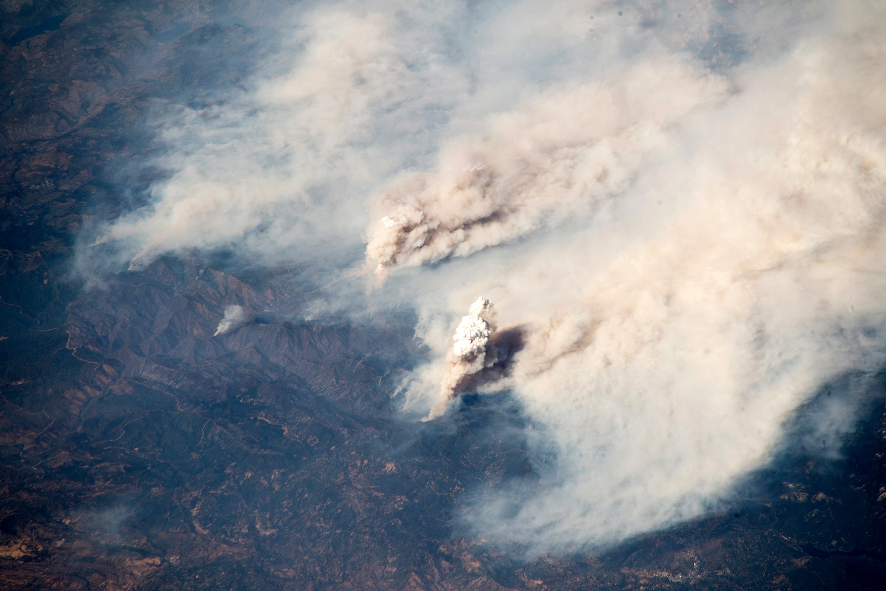 A photo taken from the ISS shows plumes of smoke over northern California.