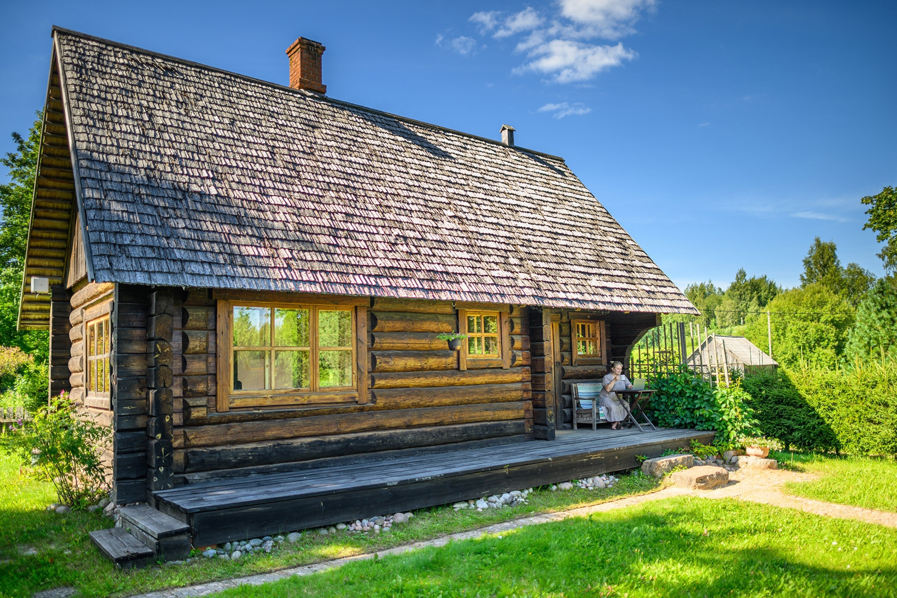 A cabin with a woman sitting out front.