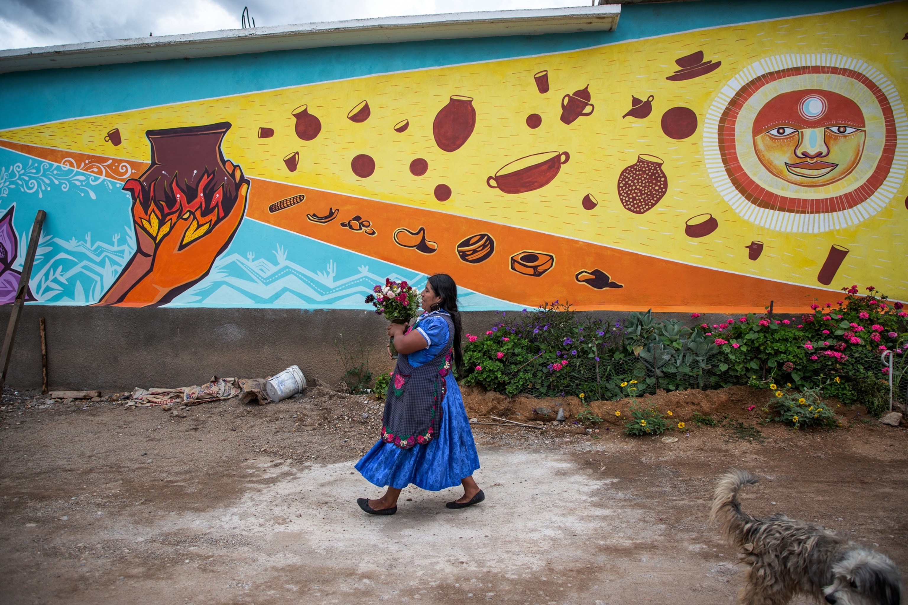 Oaxacan woman walks on the streets of Tlapazola carrying flowers