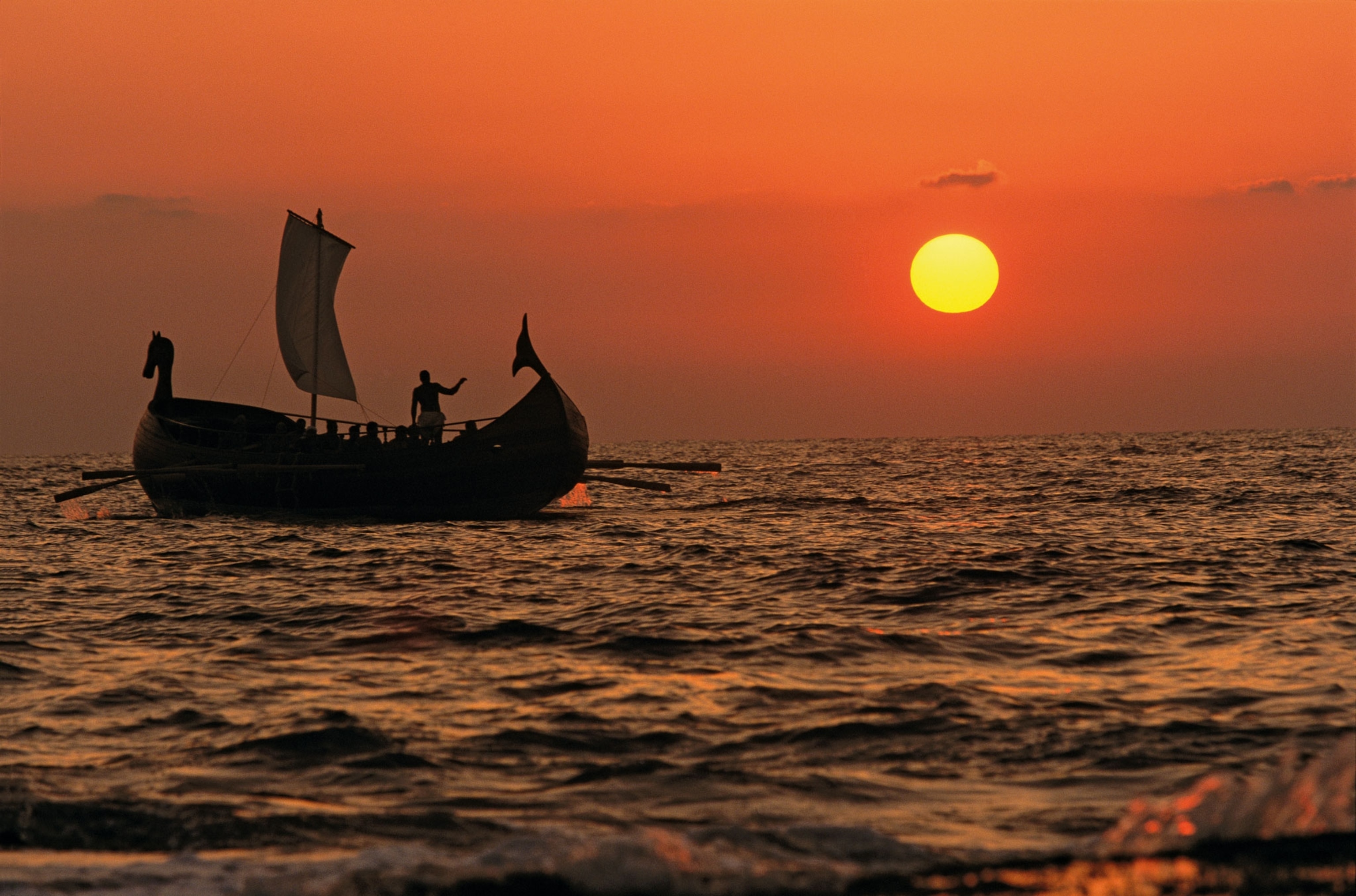 A ship sails at sunset