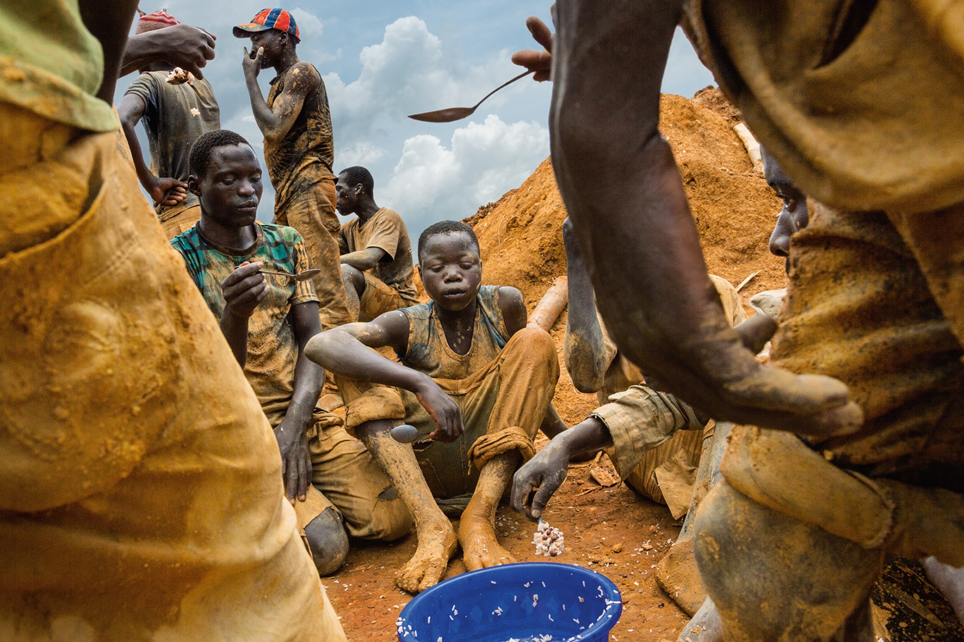 a group of gold miners waiting their turn to eat from a shared bowl of rice and beans