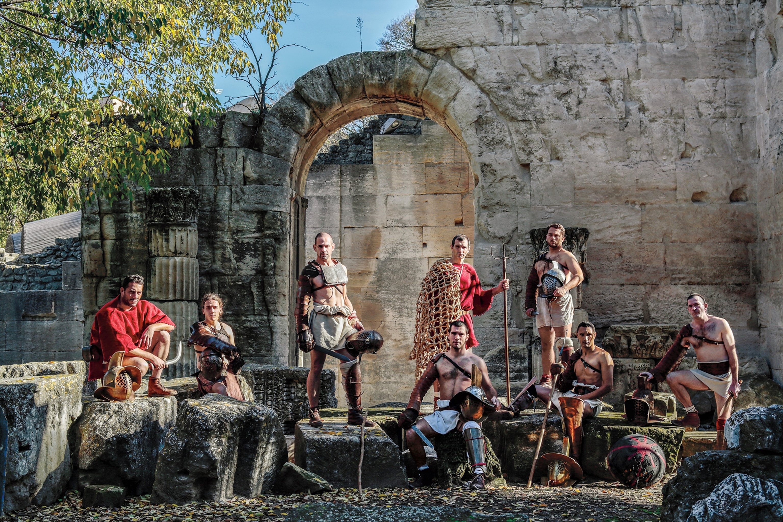 Gladiator reenactors pose amid Roman-era ruins in Arles, France.
