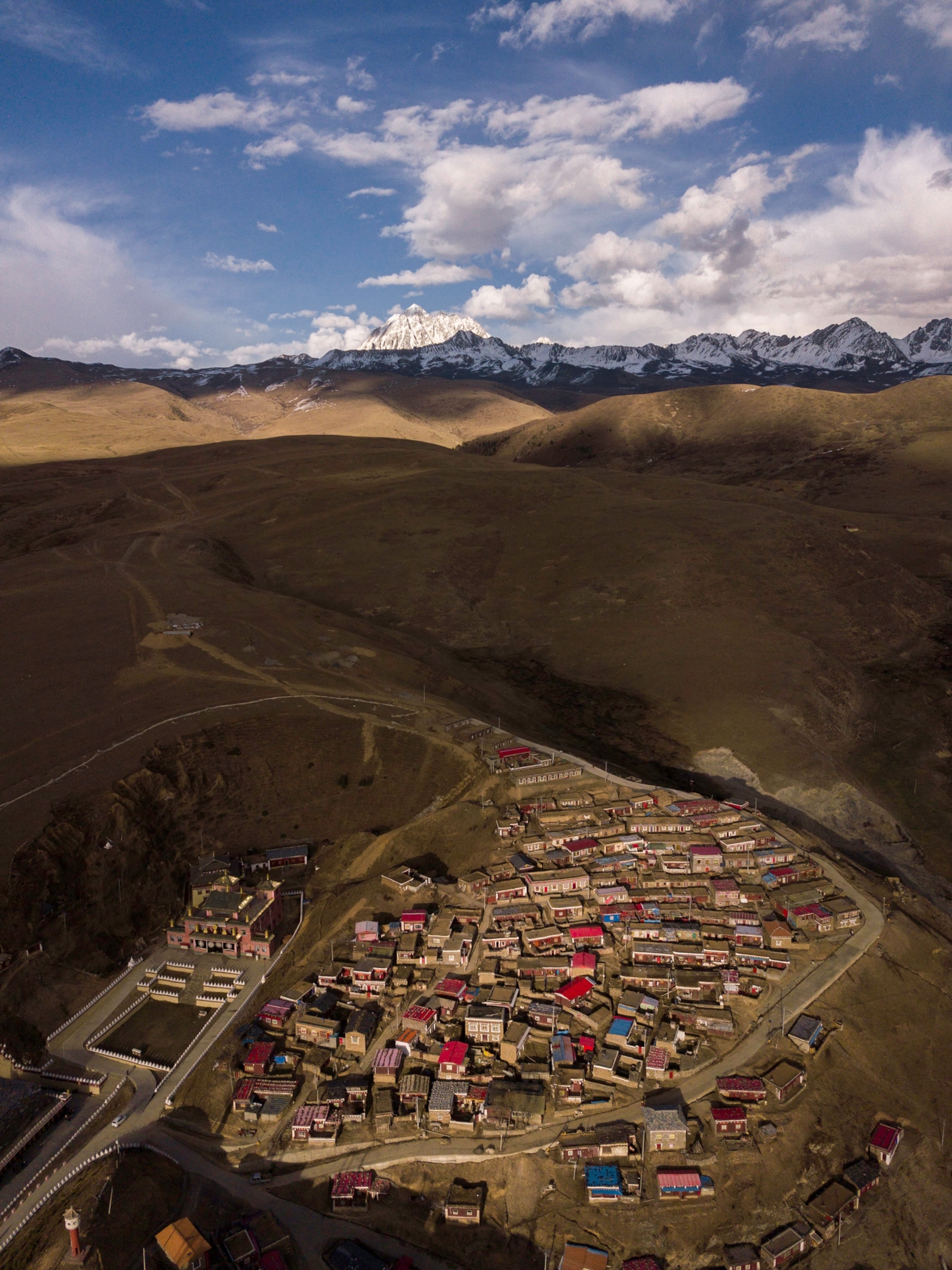 Photo of colorful village with mountains in distance.