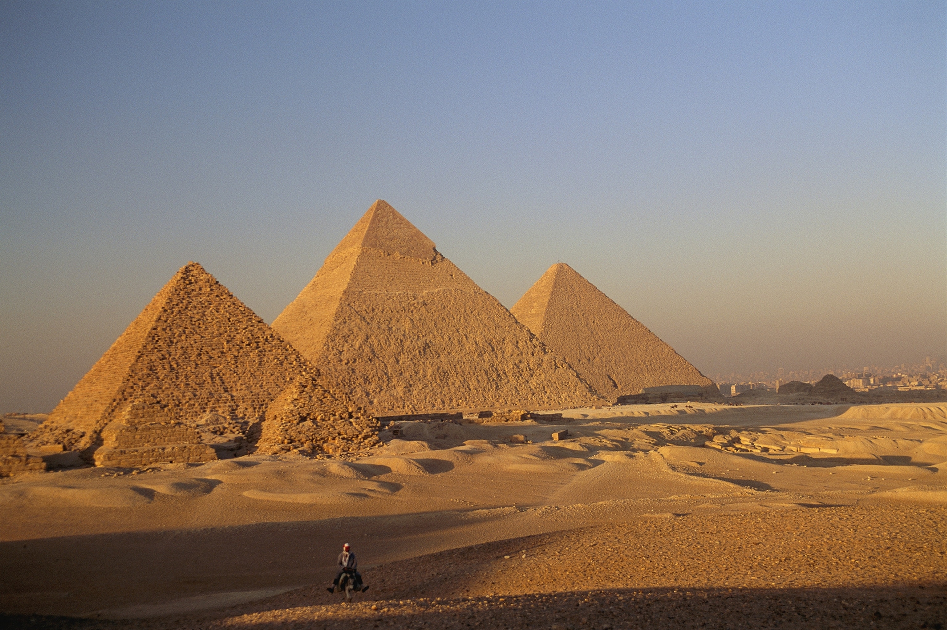 A man on a donkey in the desert near the Great Pyramids of Giza.