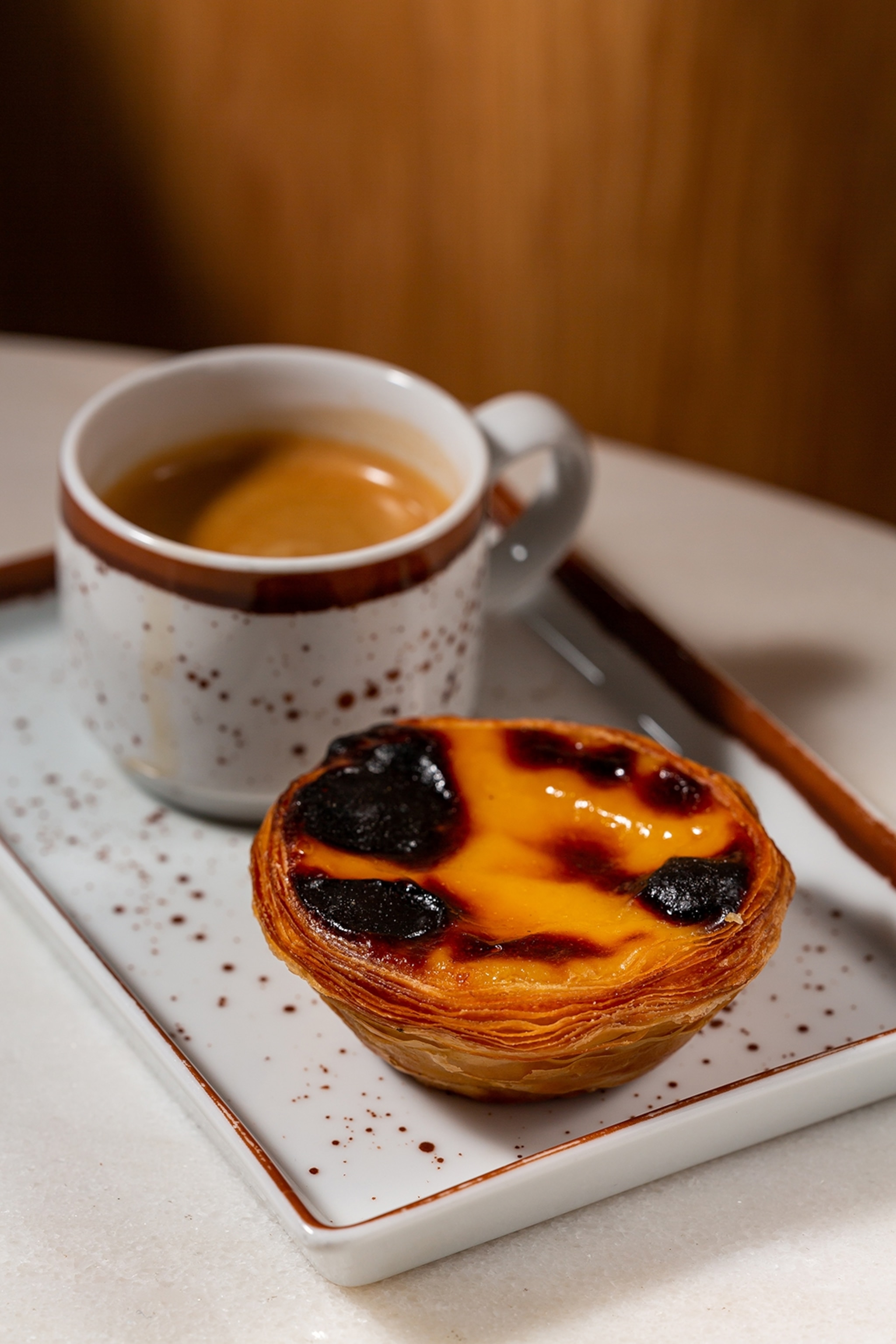 Custard filled pastry served on a plate next to a mug of coffee