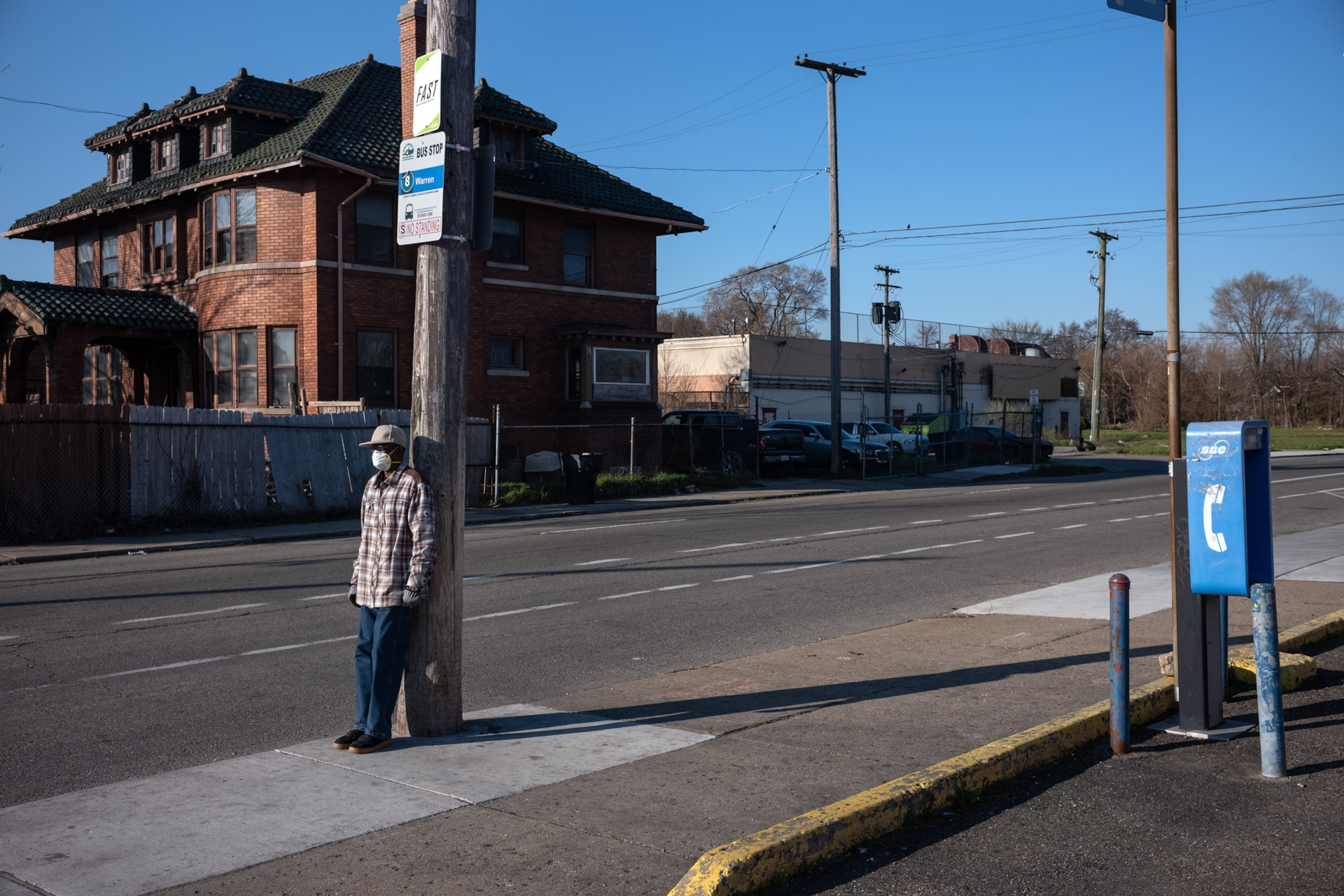 a man leaning on a light post outside during the day