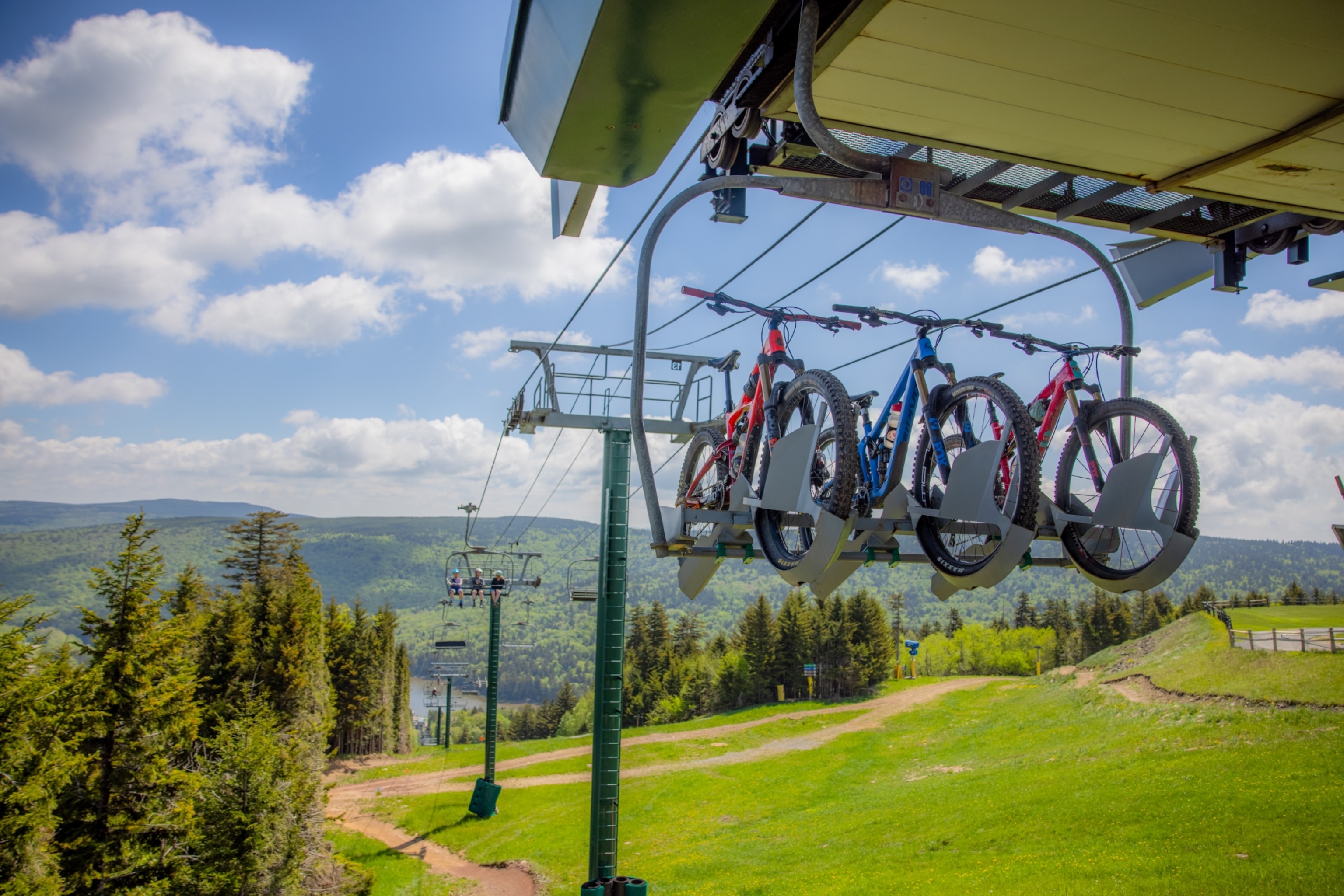 Several bikes are lifted up a mountain by a adapted ski lift