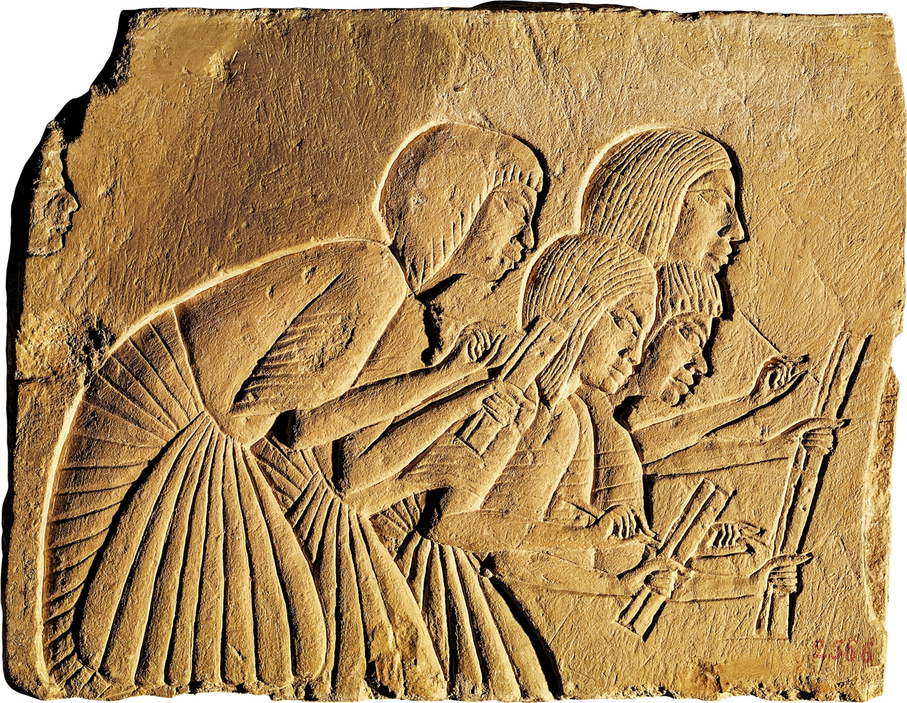 A stone relief of people leaning down with scrolls in their hands