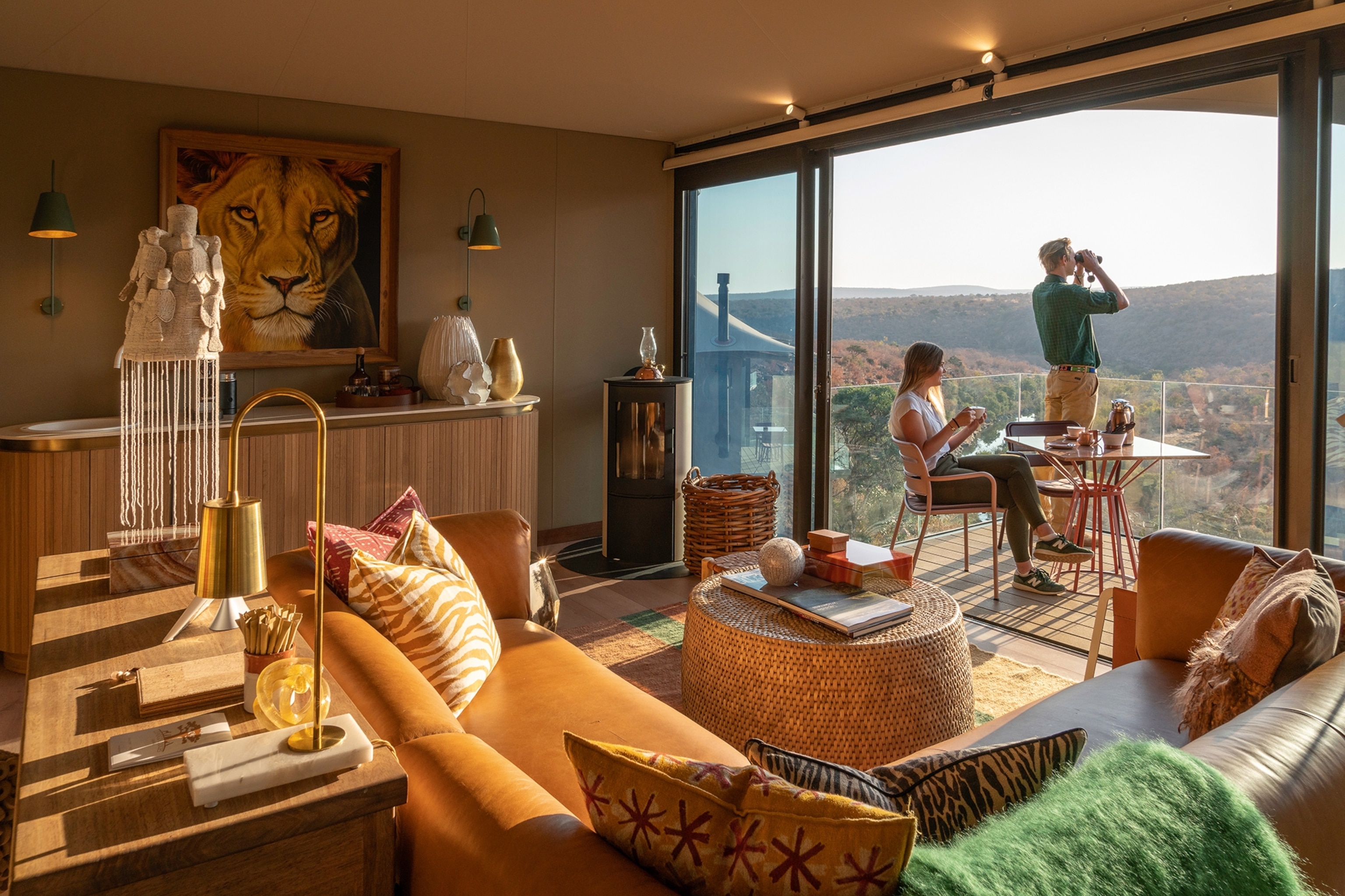 Couple look out over a desert from a room with a balcony holding binoculars