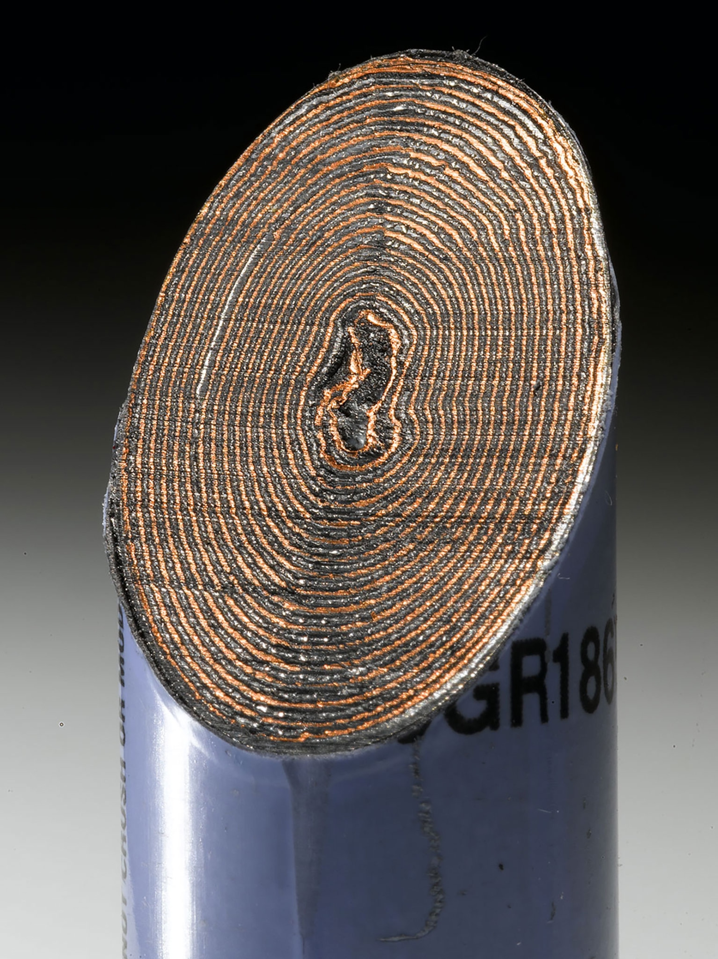 a battery, sawed in half at an angle, exposes several copper rings growing from small to big from inside out.