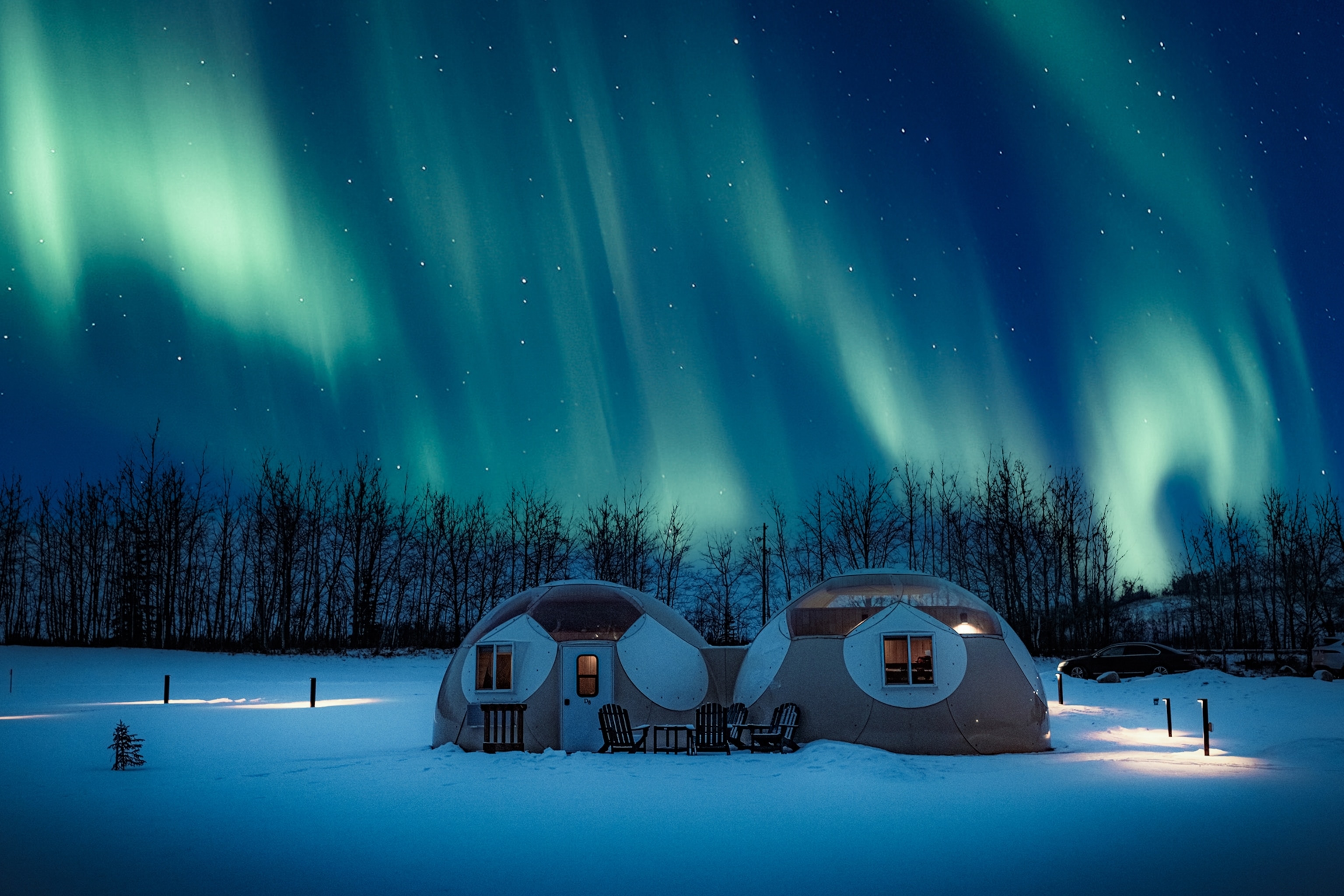 Two domes are lit up with the Northern Lights.