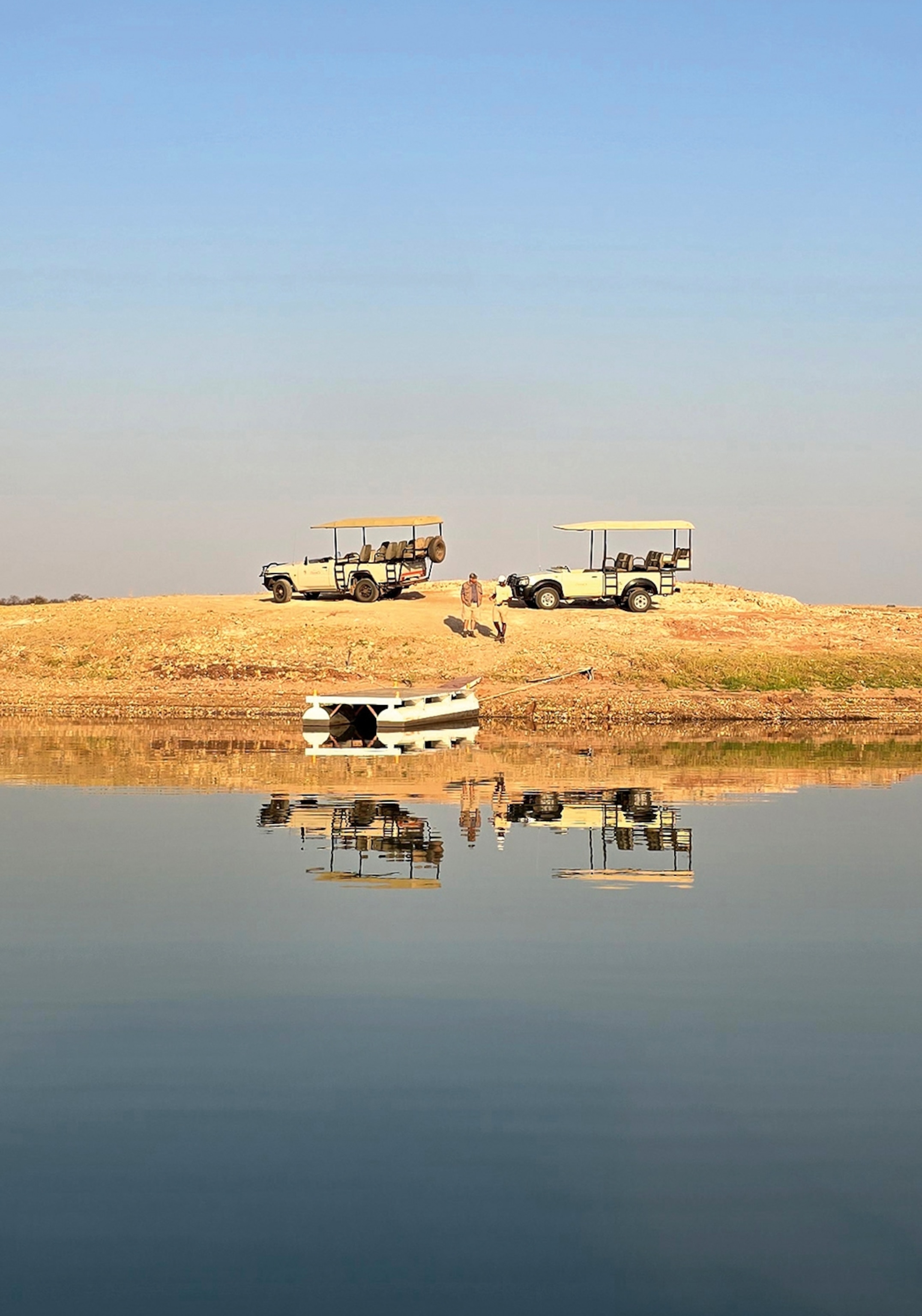 Safari vehicles by a lake
