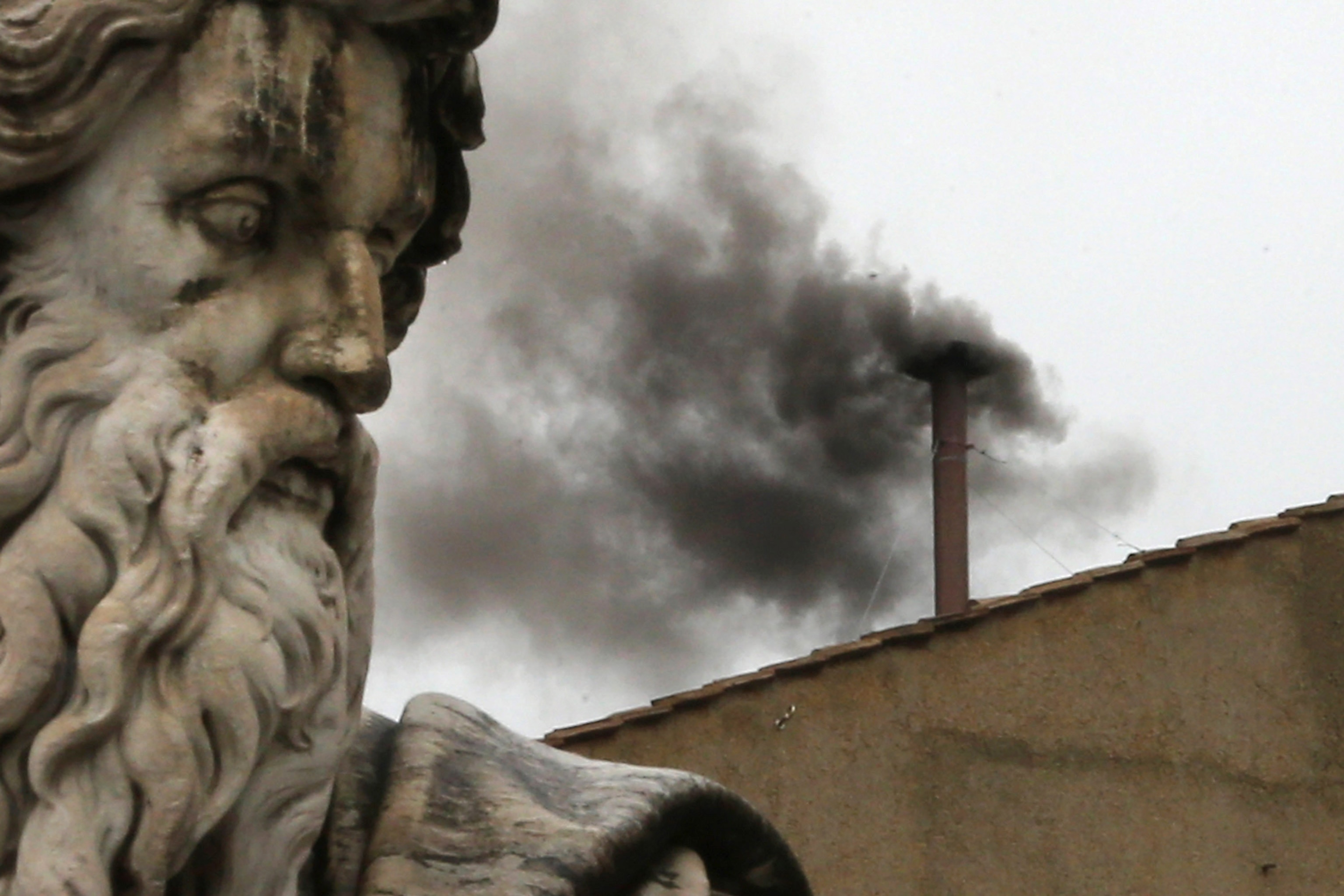 Black smoke billows from the diminutive chimney on the roof of the Sistine Chapel.