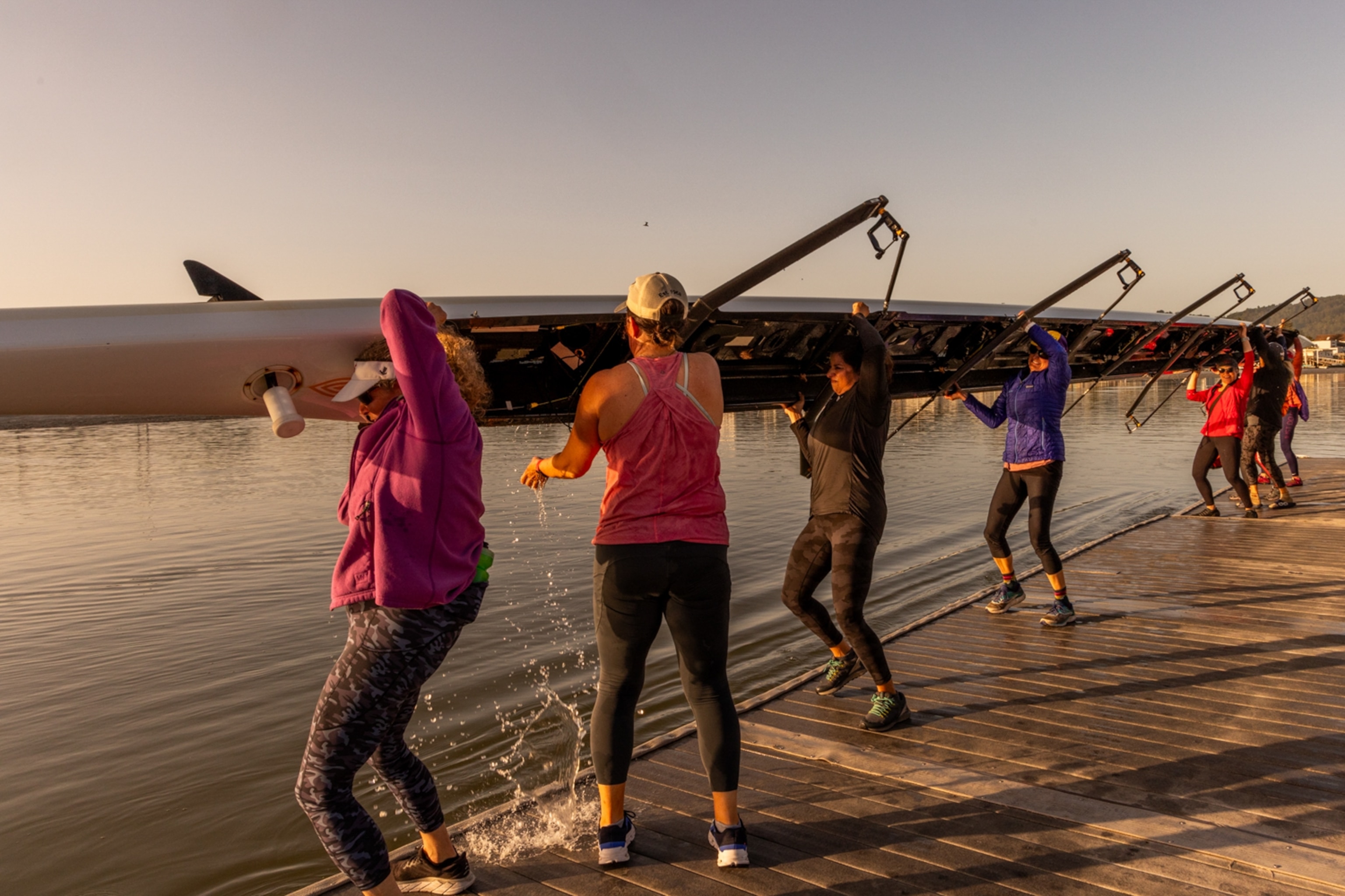 A group of women lifting a boat together.