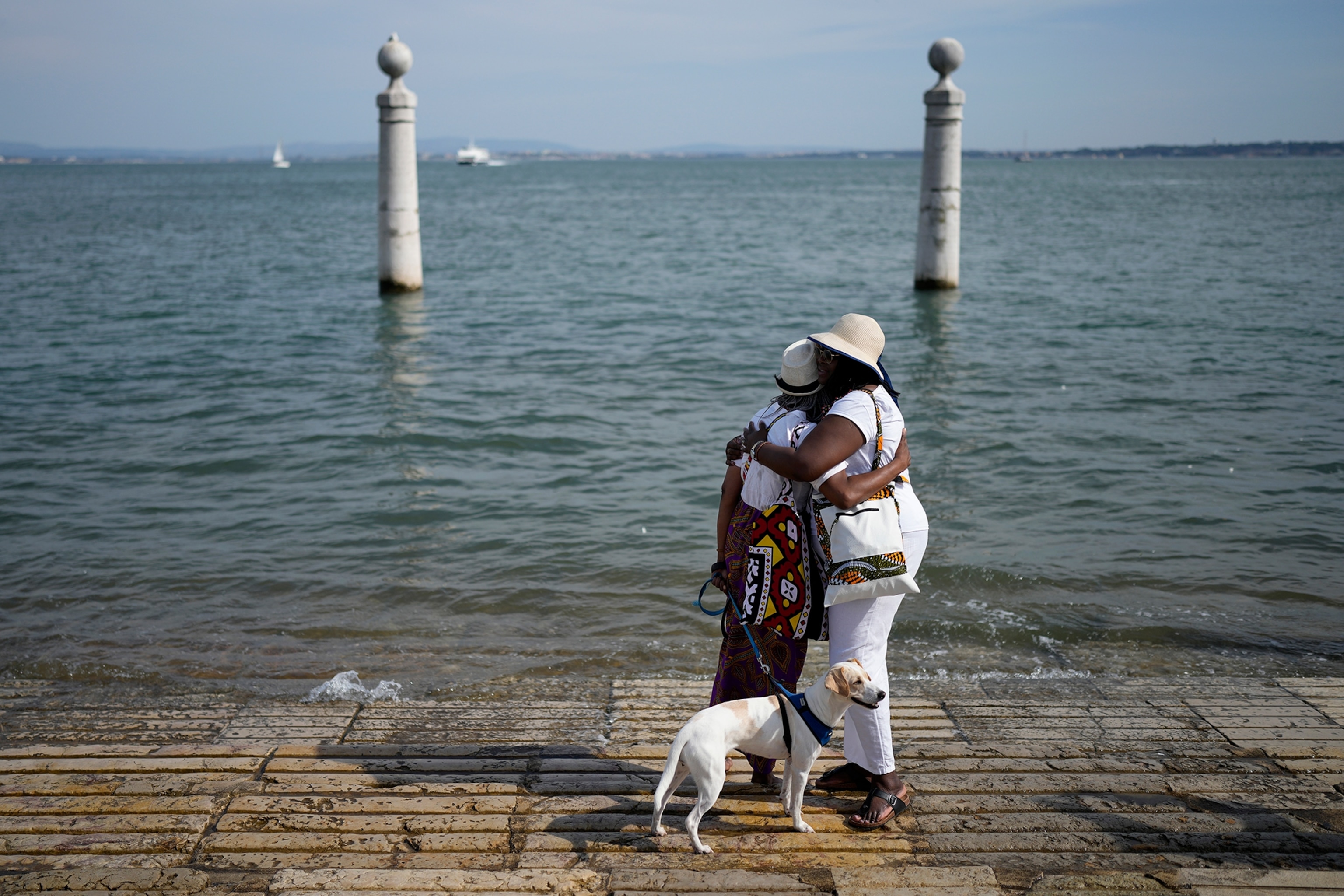 Two women embrace after throwing flowers into the Tagus river at the end of a ceremony to remember the victims of the Atlantic slave trade.