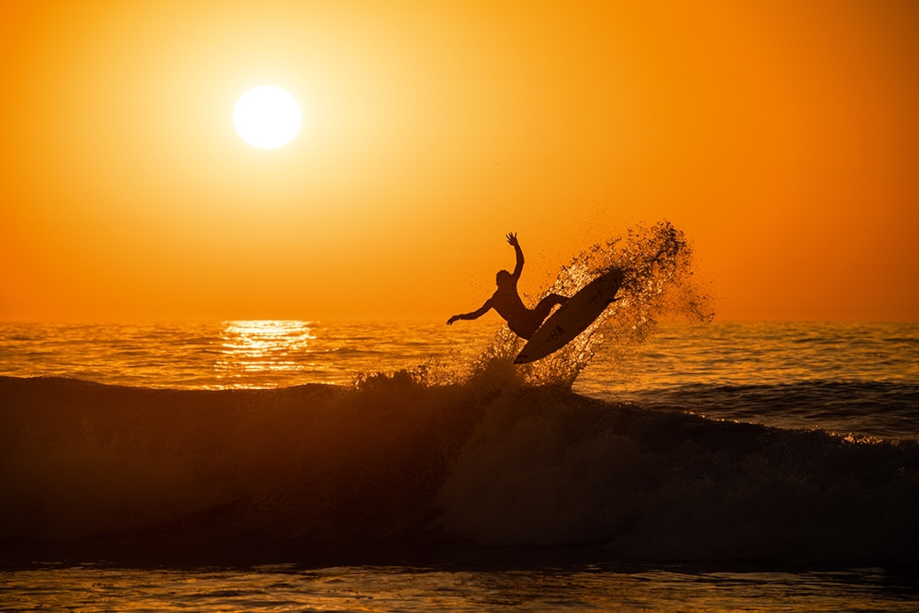 A surfer on a wave at sunset