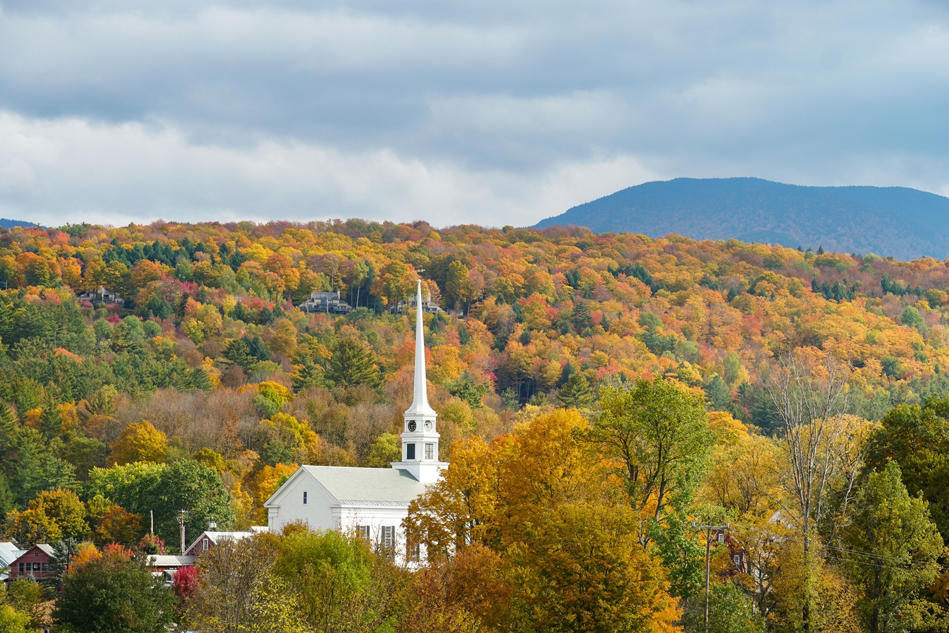 The striking white Stowe Community Church in Stowe, Vermont, stands out in the surrounding fall foliage.