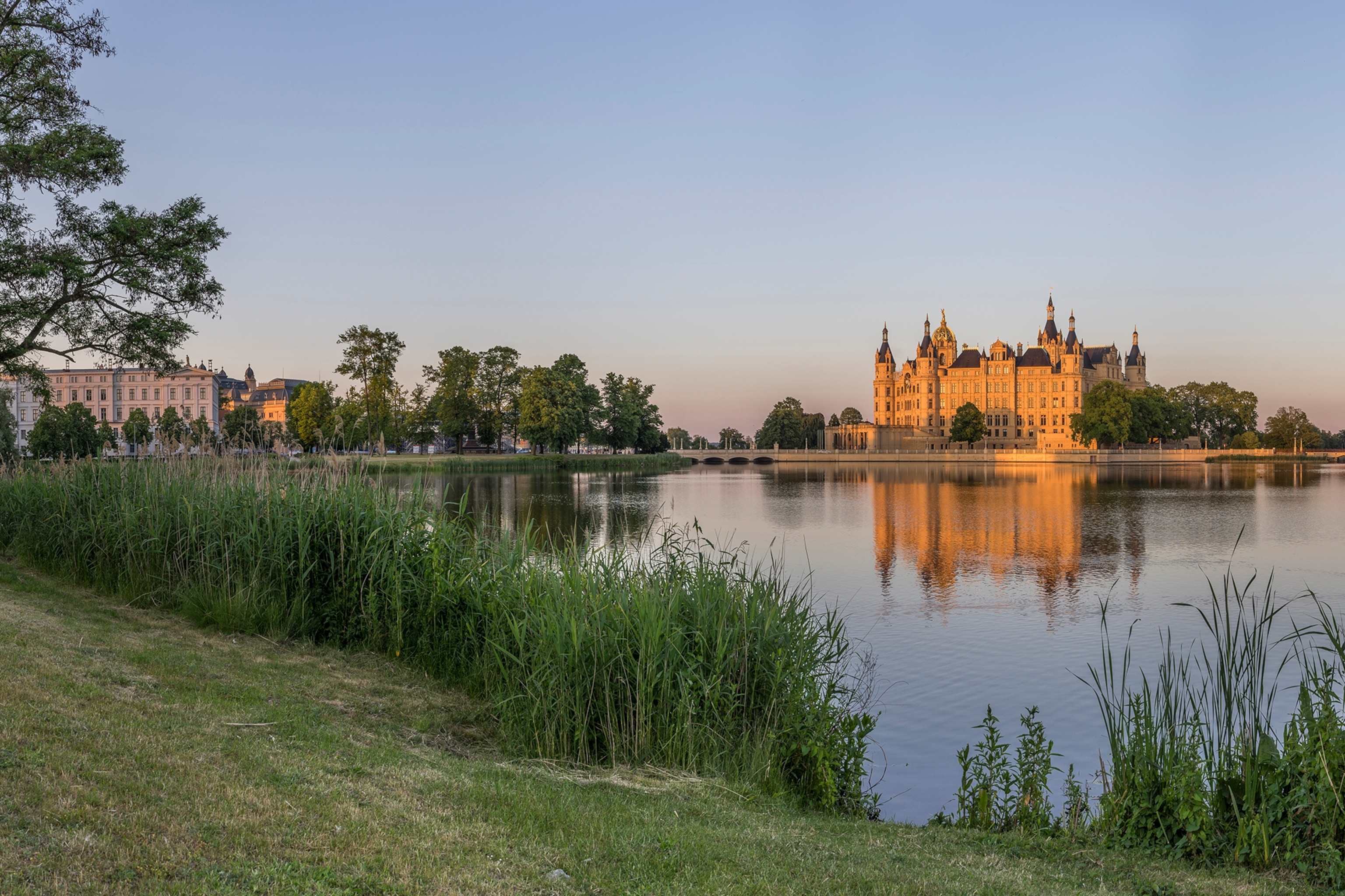 Castle surrounded by a lake and grassland, reflecting on the water