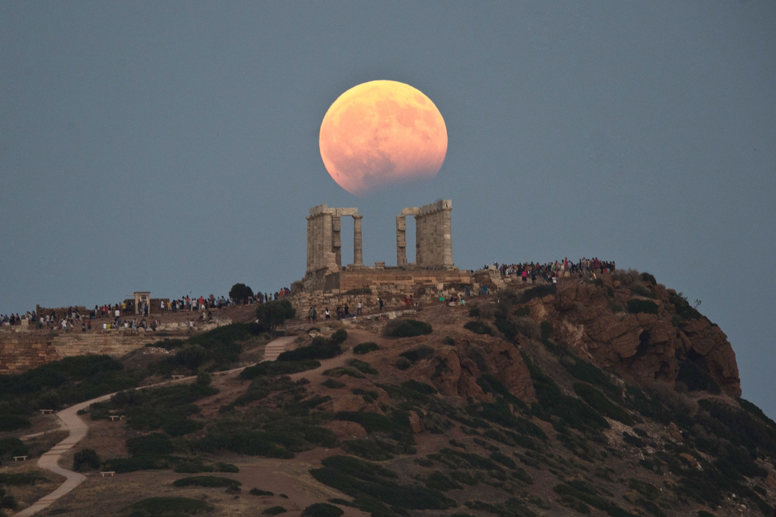 The August full moon, which is accompanied by a partial lunar eclipse, rises above the 5th Century B.C. Temple of Poseidon at Cape Sounioin Greece.