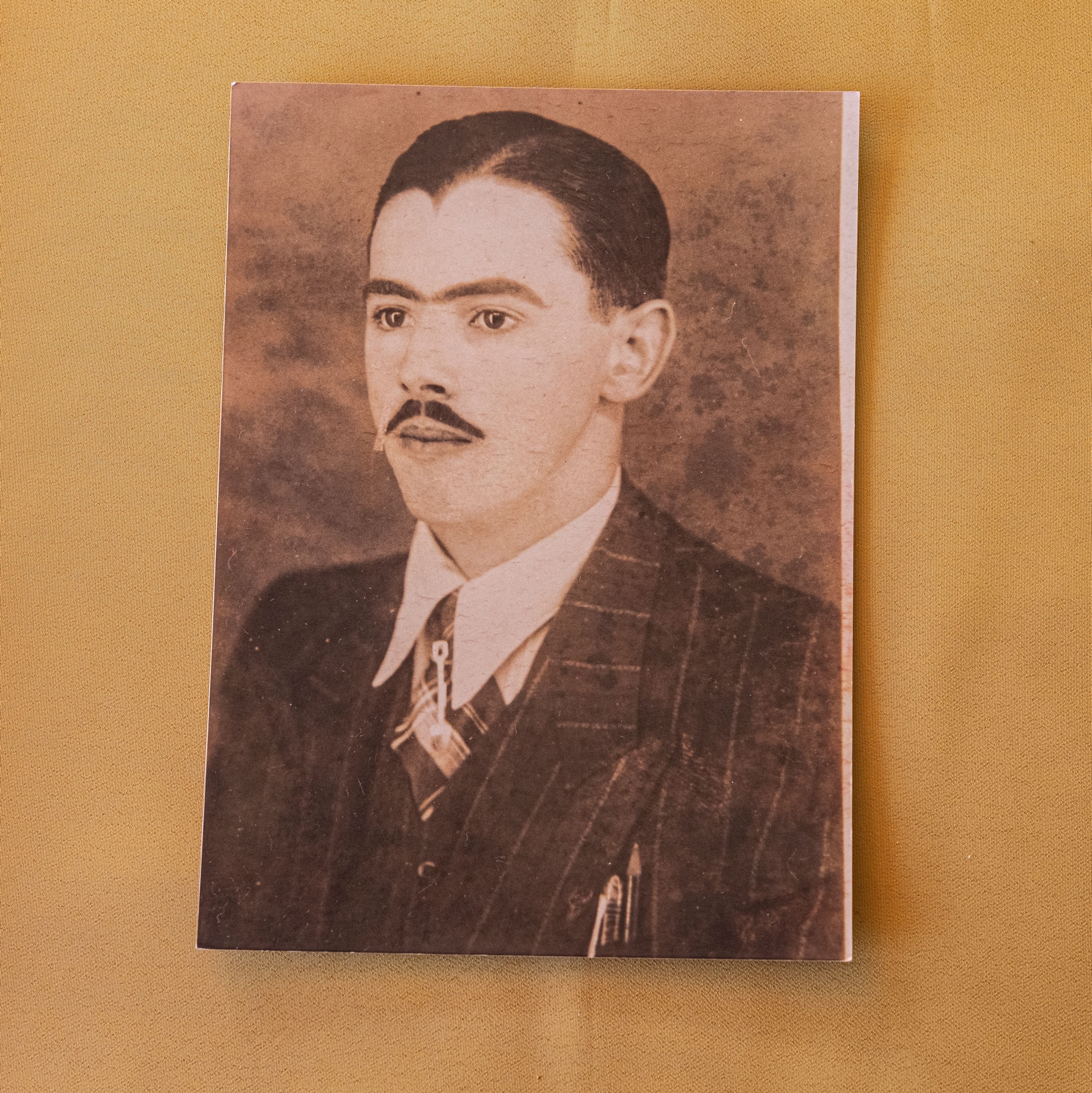a photo of a man dressed in a suit with slicked black hair and a mustache.