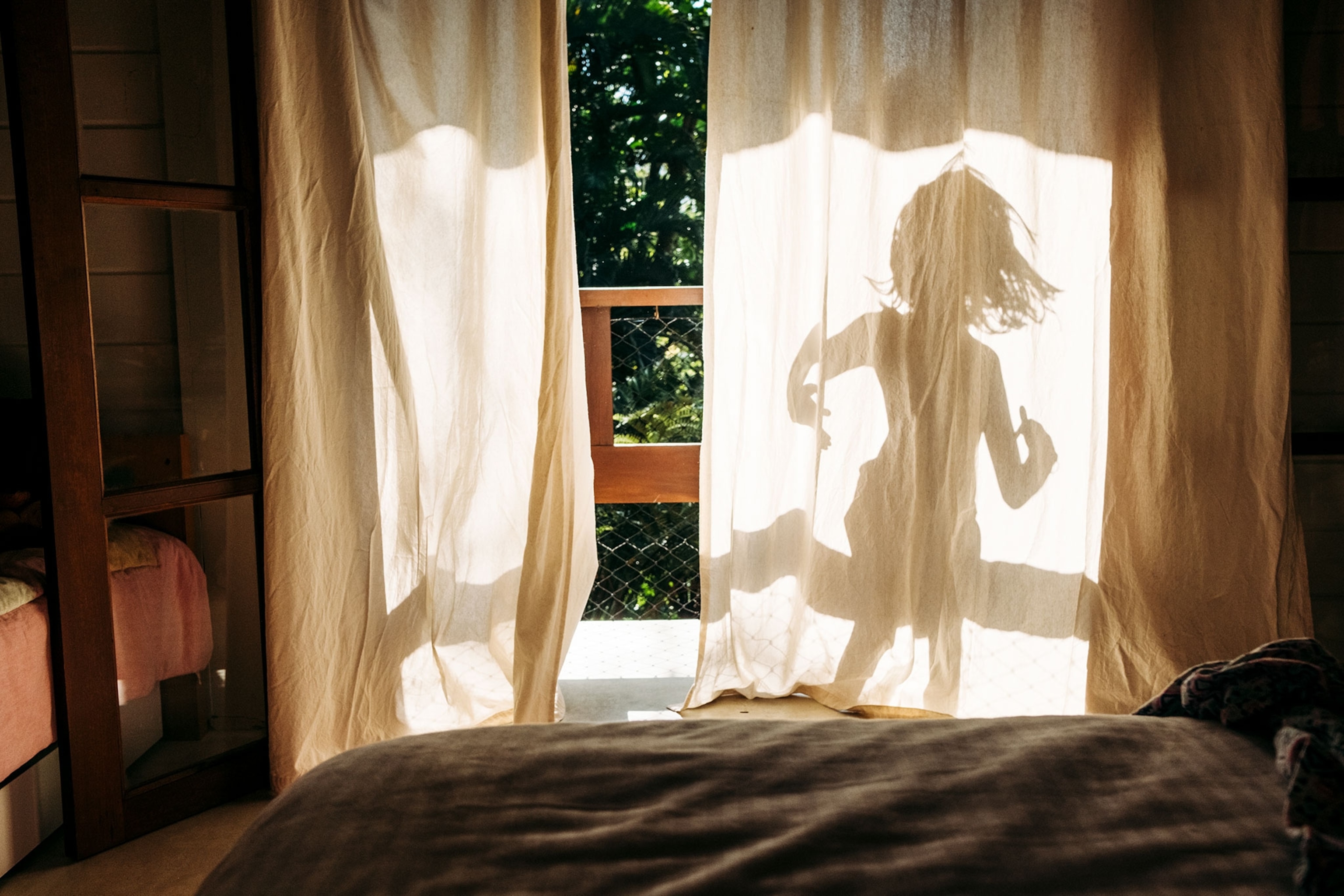 a girl's silhouette showing fro behind a curtain
