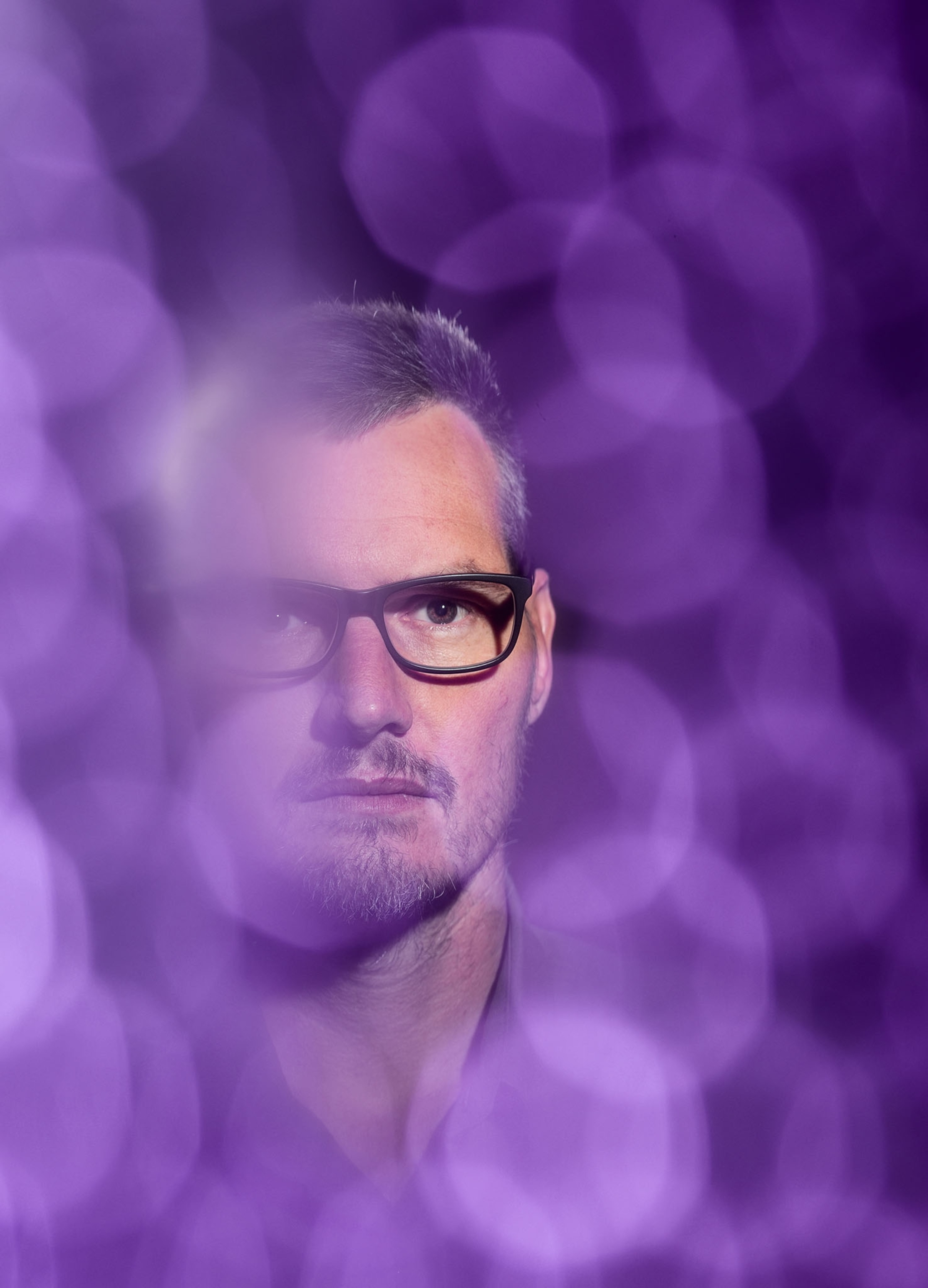 man in eyeglasses on purple background.