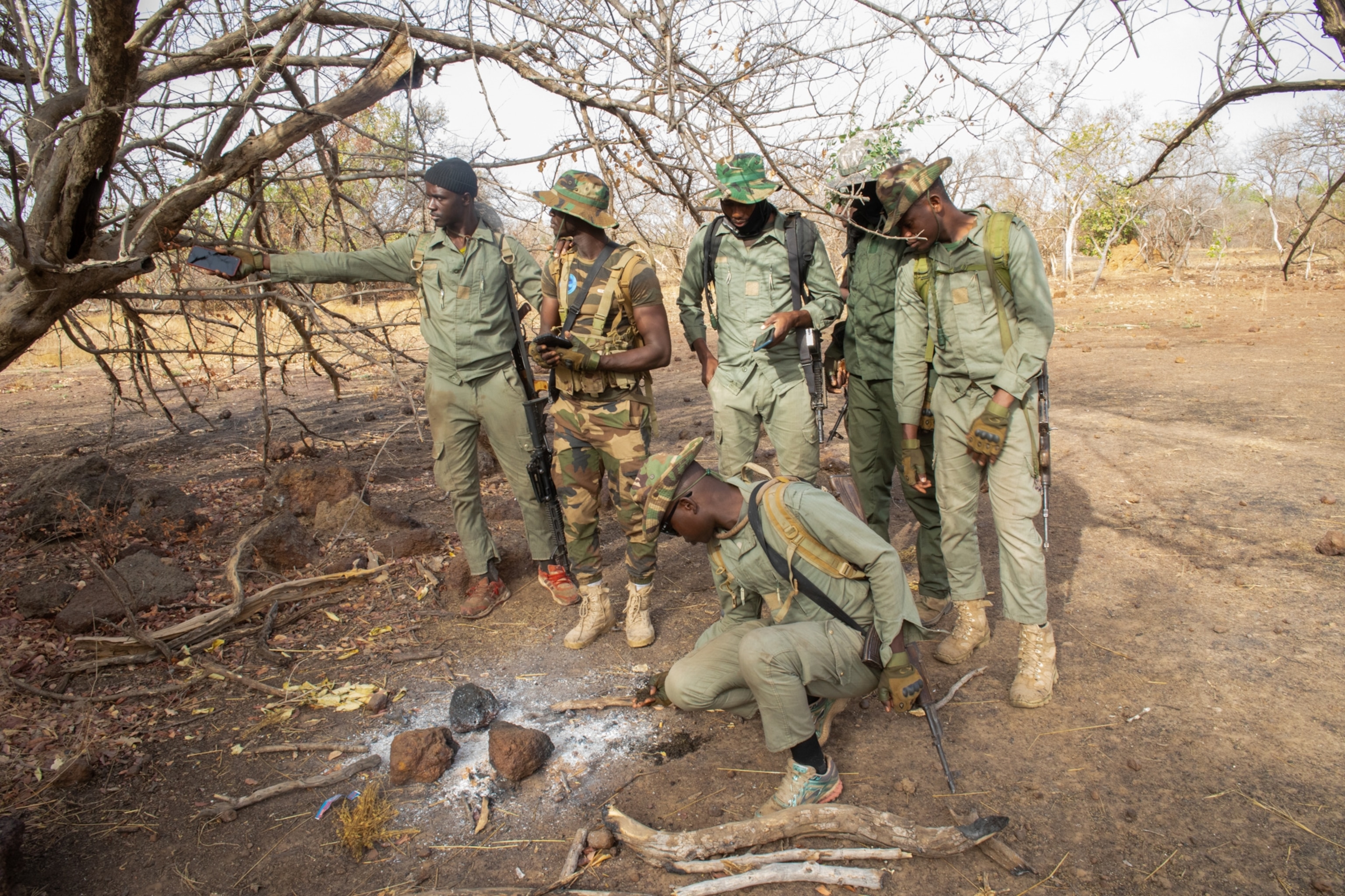 Picture of a team of rangers investigating the remains of a fire at a poacher camp.