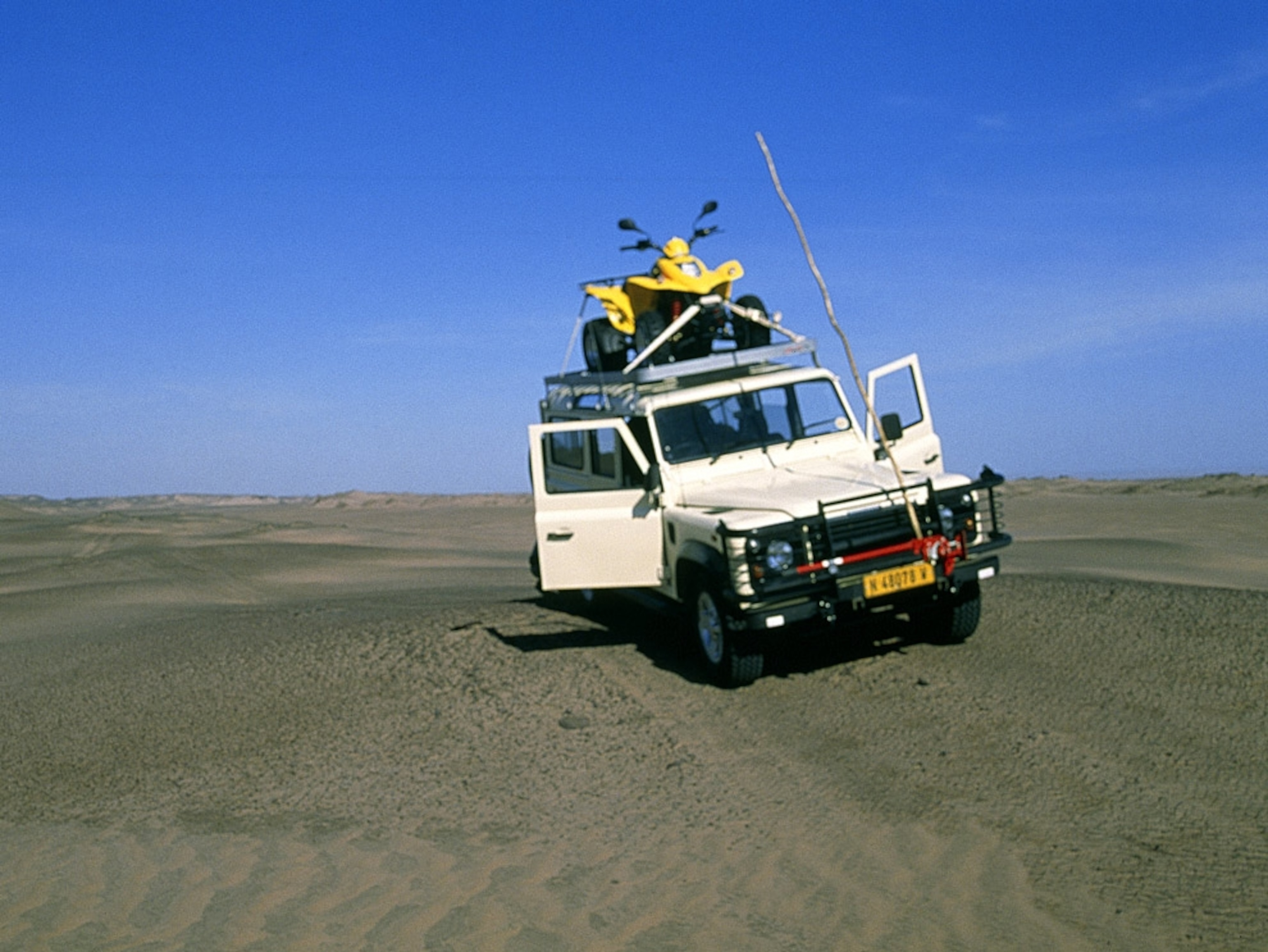 Jeep vehicle with an ATV on top in an African desert