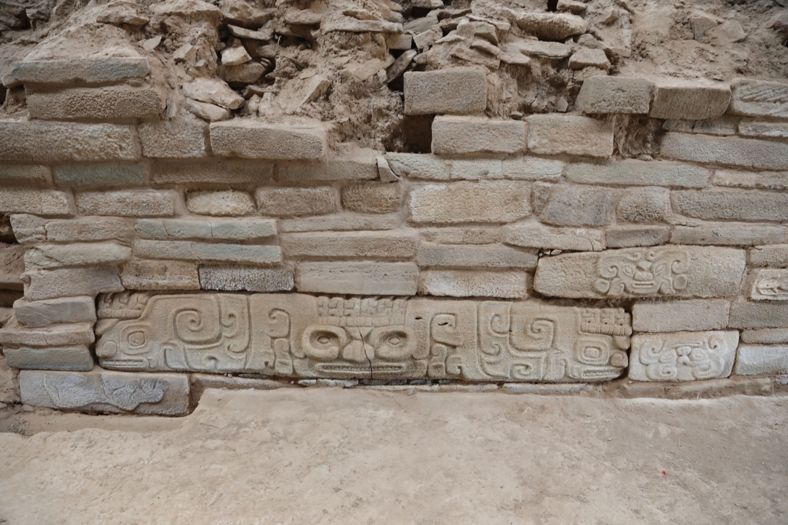 a stone carving of a face at the bottom of a stone wall