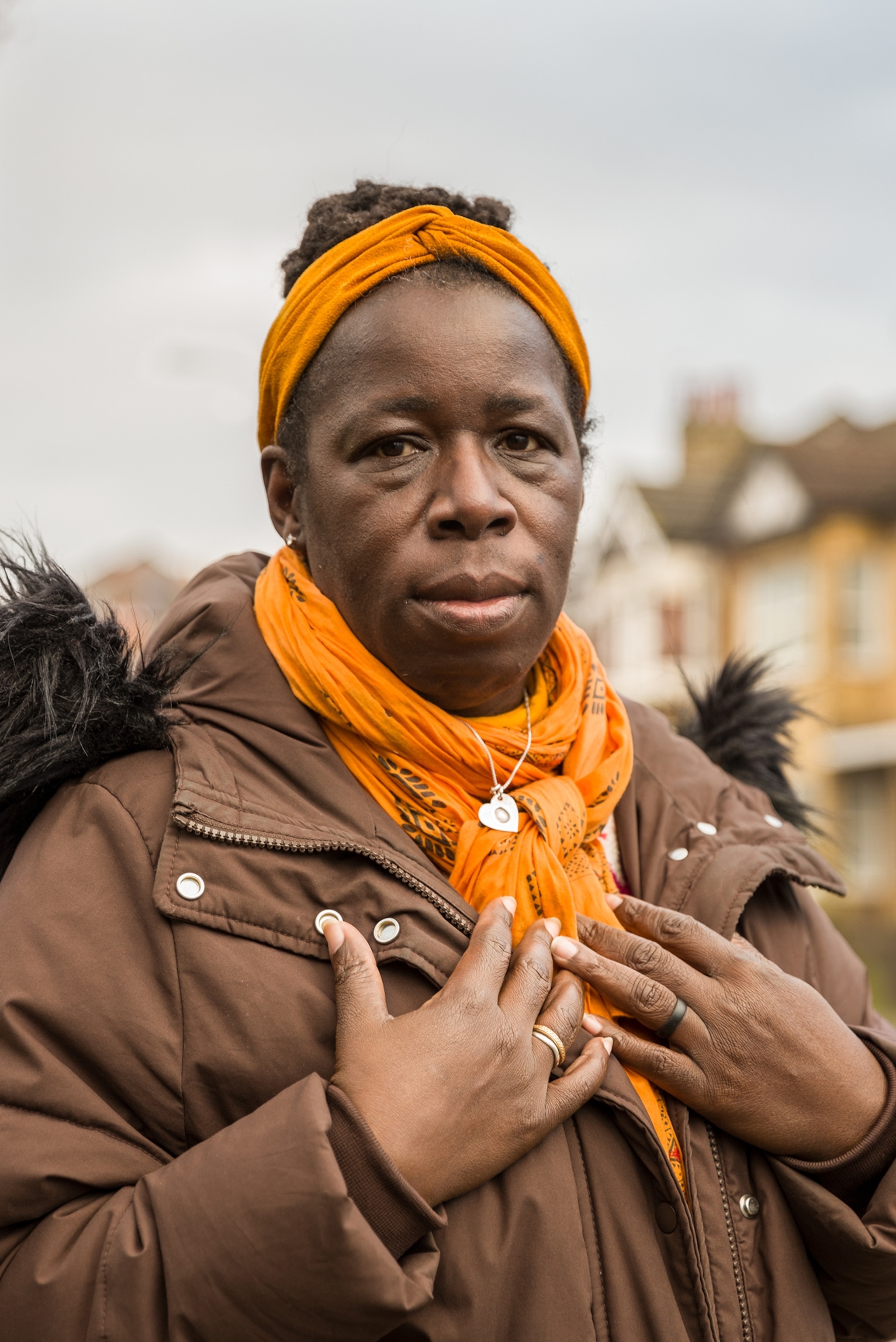 Picture of woman in orange headscarf and heart-shaped medallion.