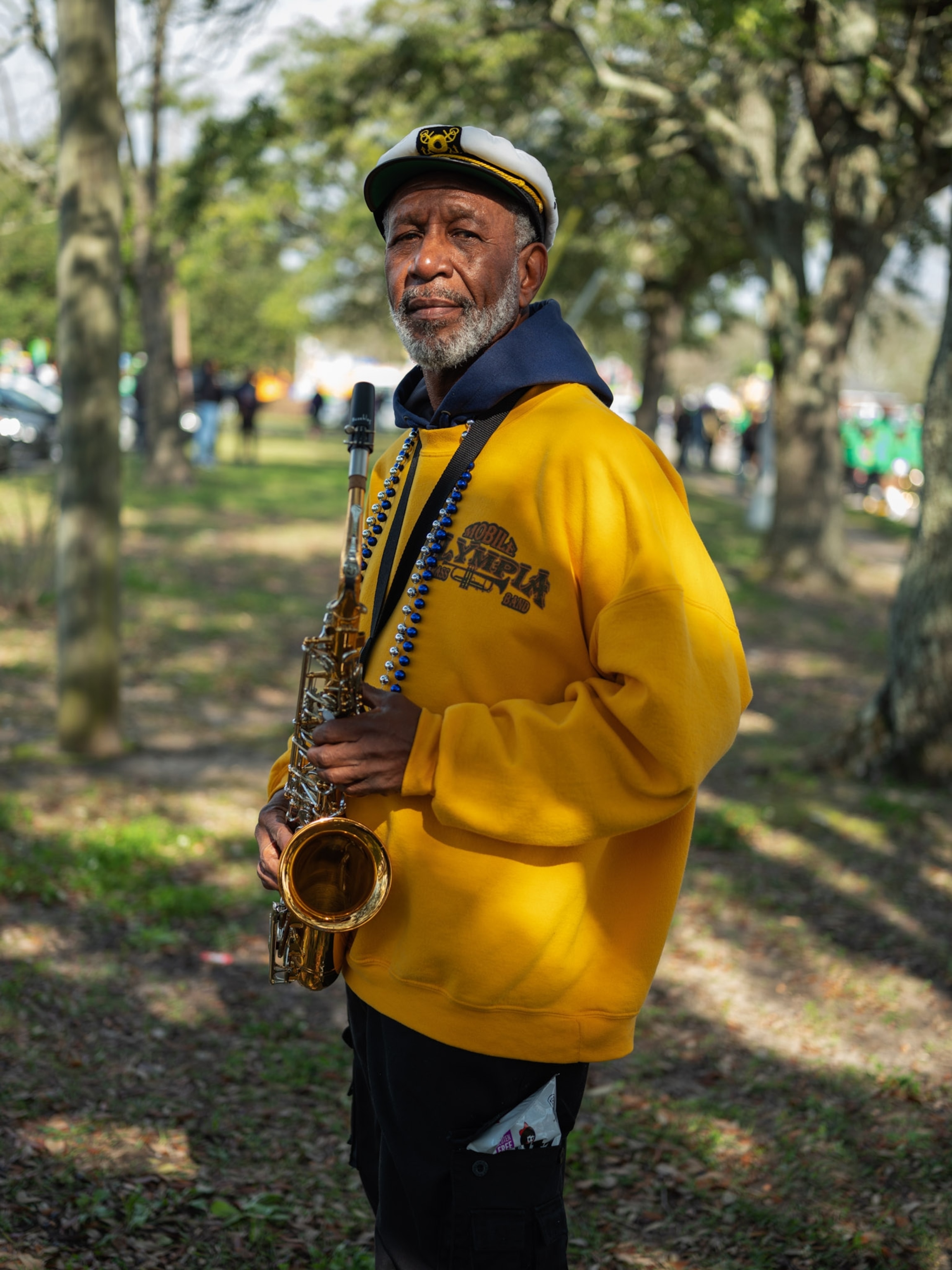 a man in a yellow pullover holding his saxophone