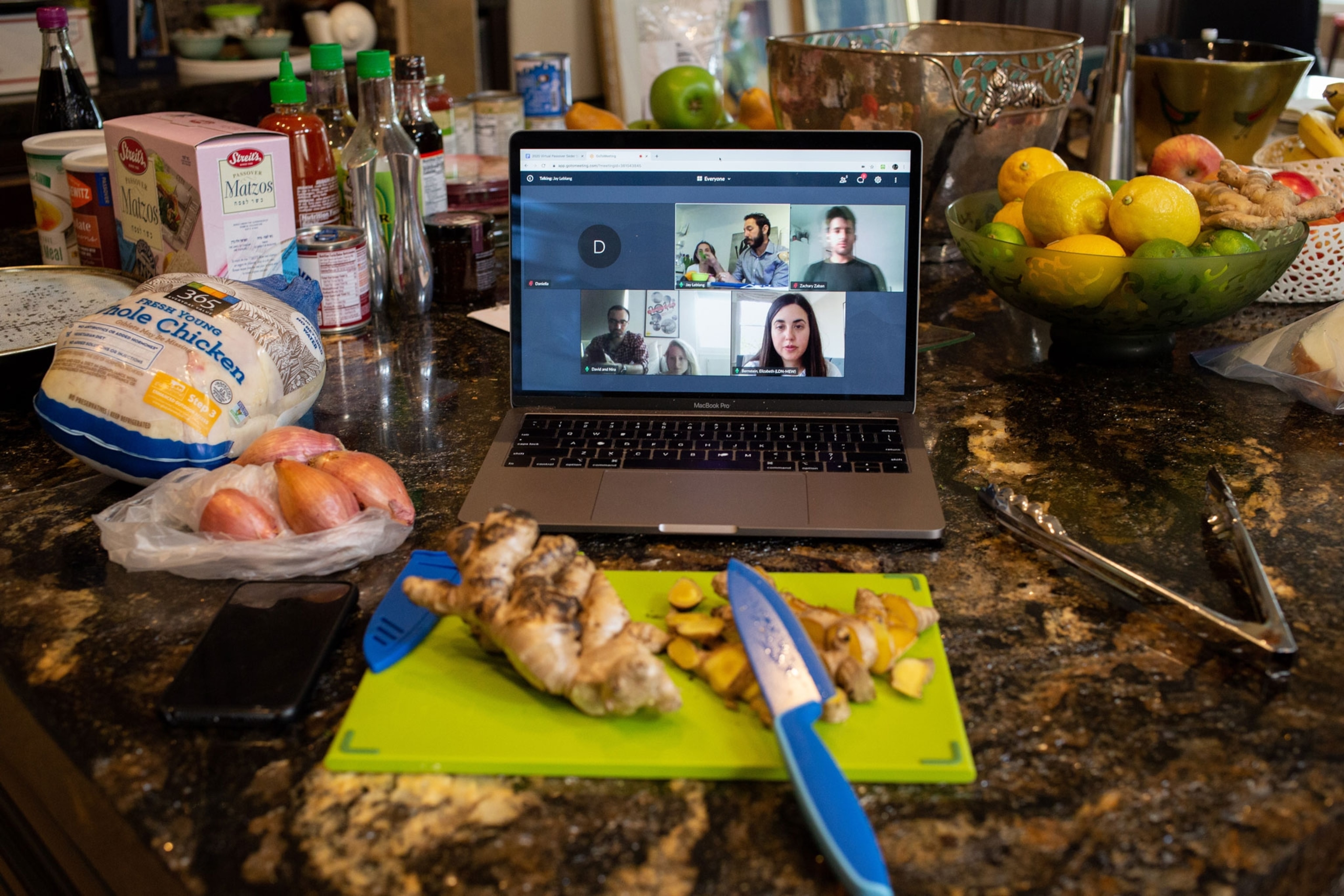 a person preparing food while video chatting with other people