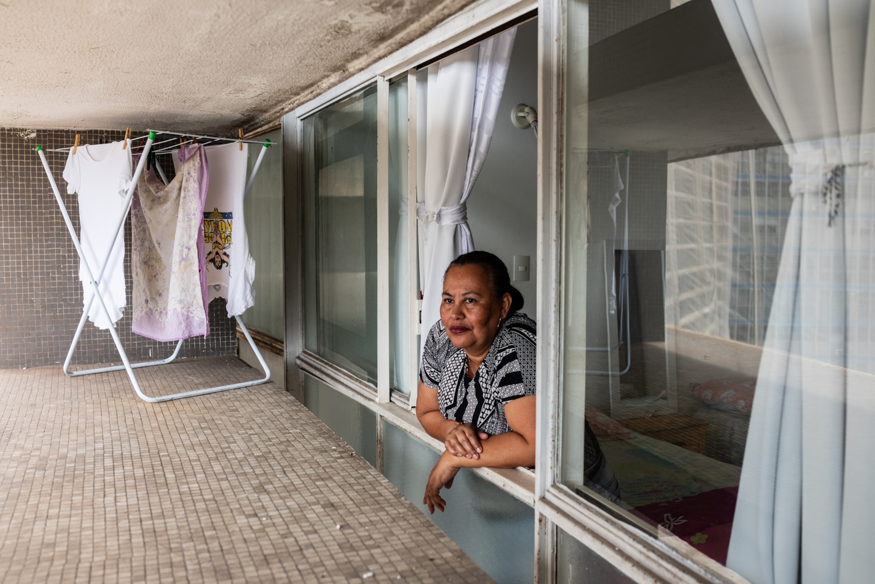 a woman leaning outside of her window doing laundry