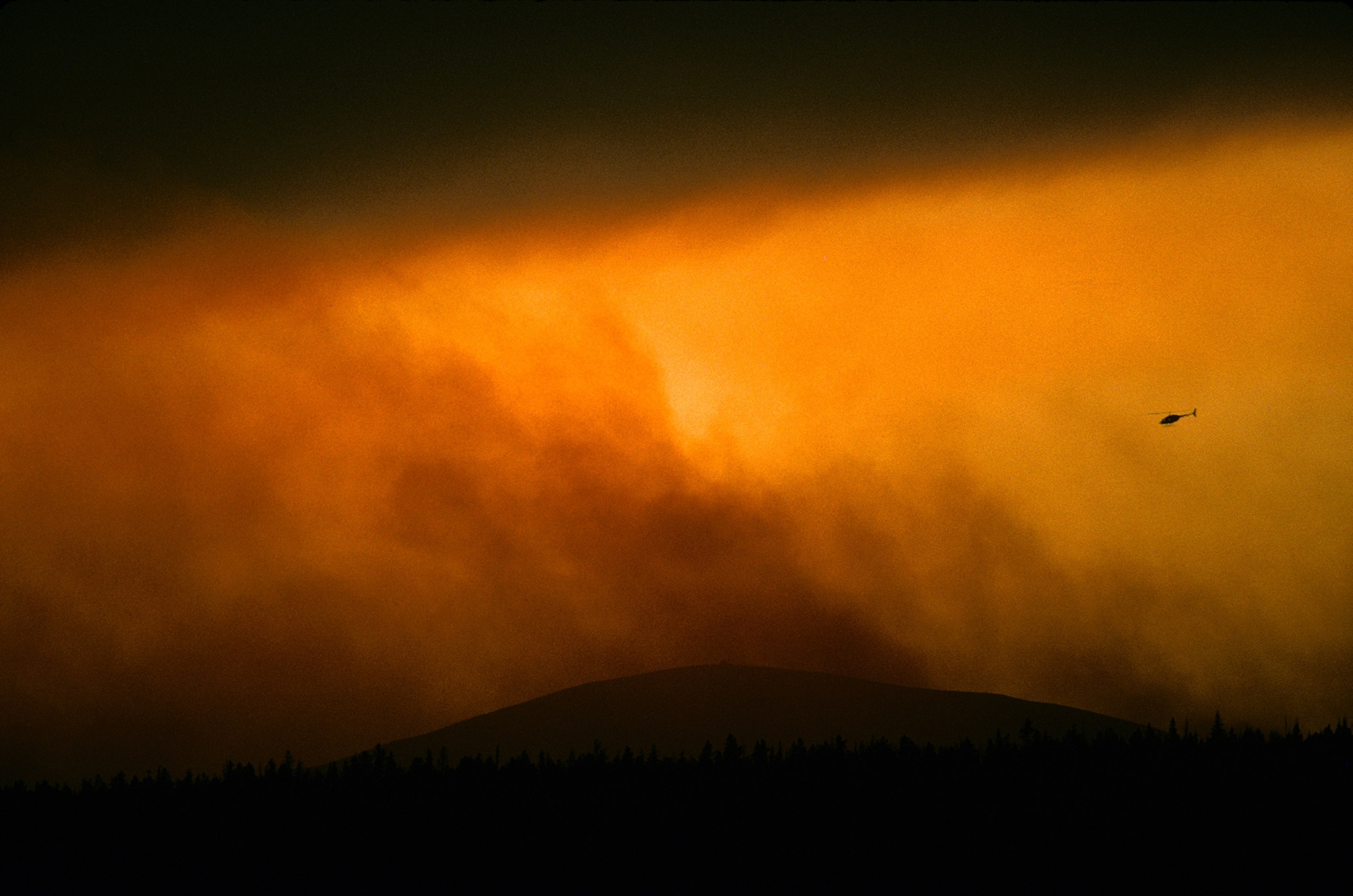 Helicopter flies over forest fires in Yellowstone National Park, Wyoming.