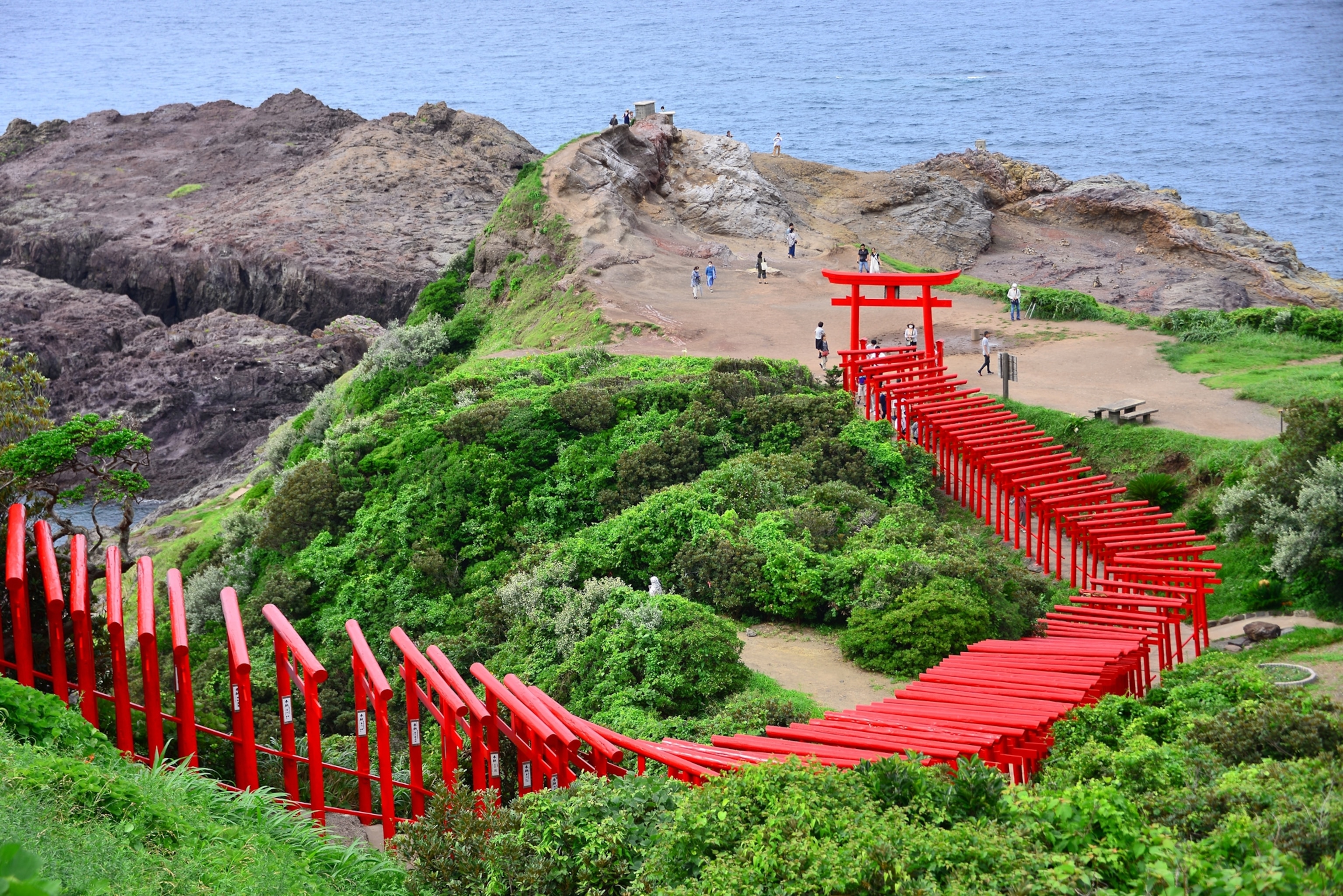 A PHOTOGRAPH OF Motonosumi Shrine (Motonosumi Jinja), WHICH HAS 123 RED torii gates, along the coast of the Sea of Japan.